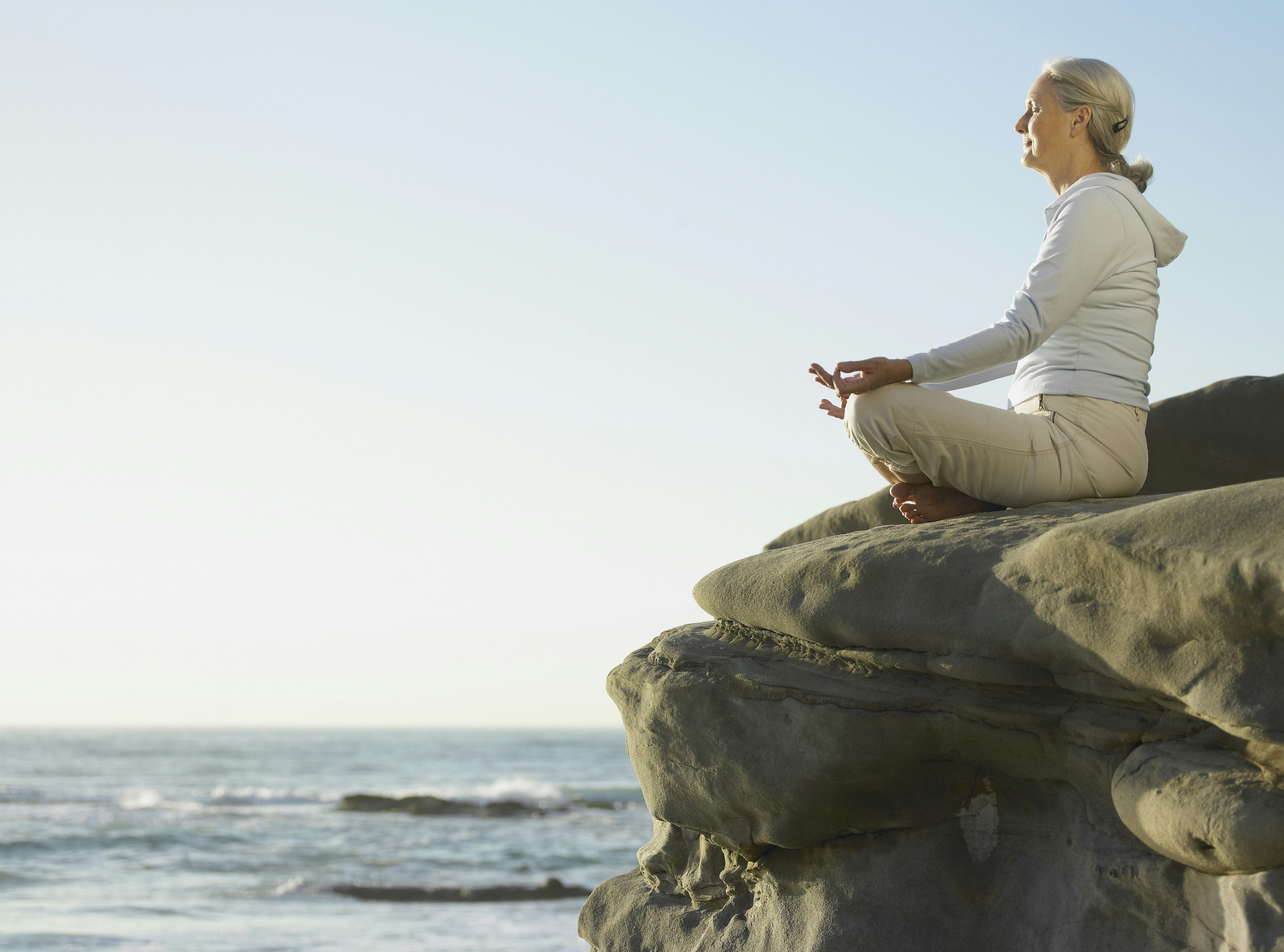 A woman mediates on a cliff over looking the pacific ocean near San Diego © Brad Wilson / Getty Images