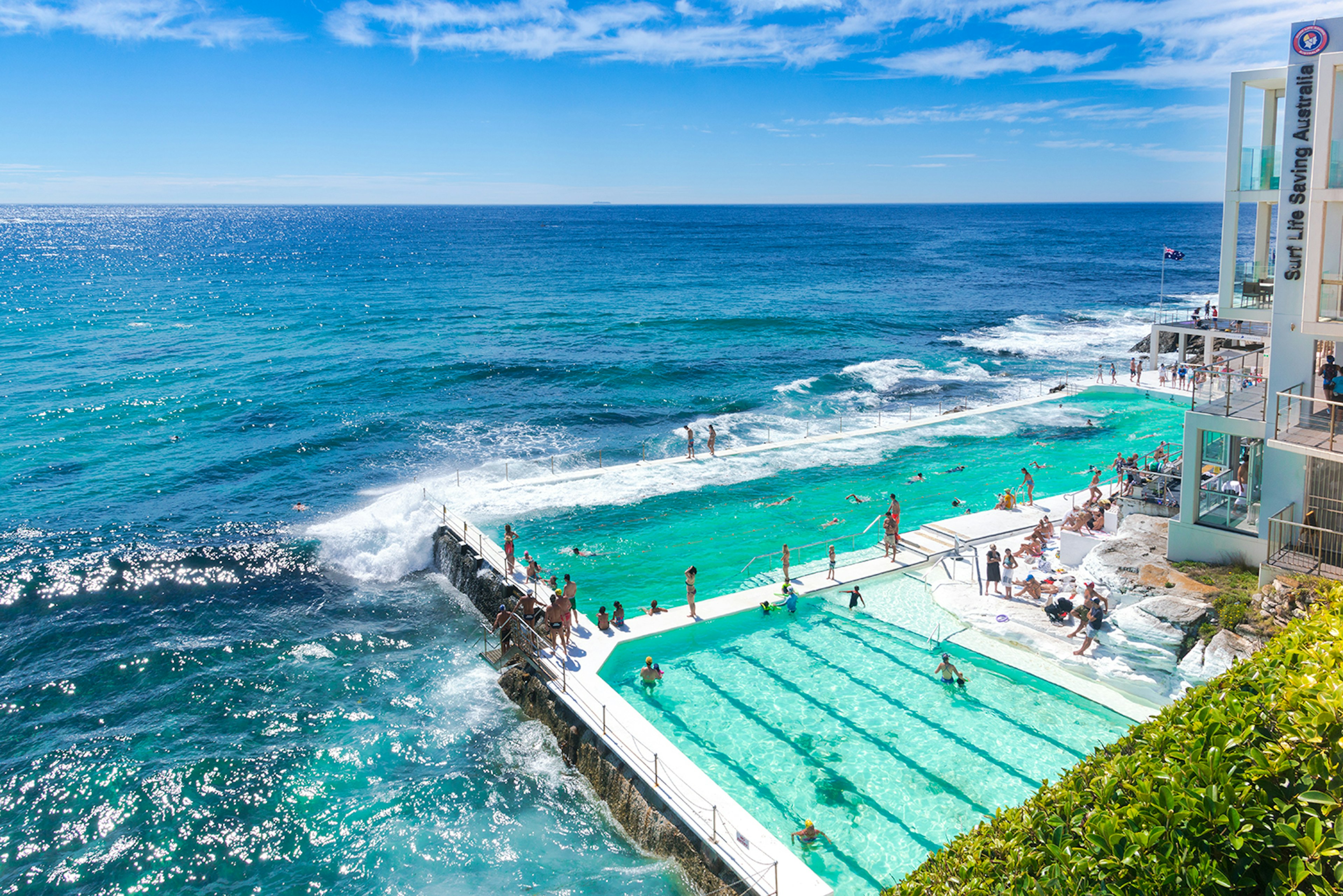 Swimmers and sunbathers at two pools that are thrashed with waves from the adjacent ocean