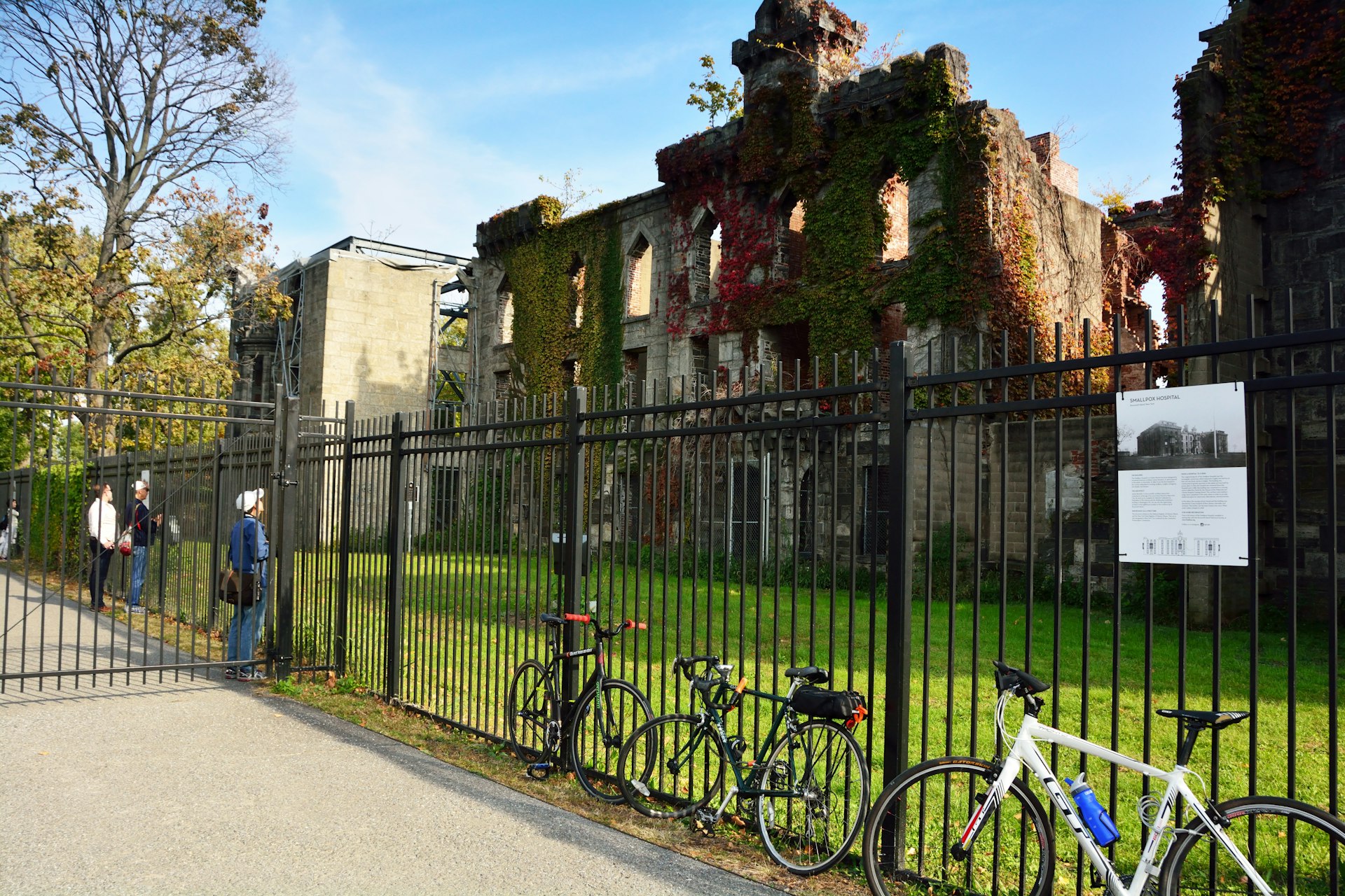 People outside the fence at the ruin of Smallpox Hospital, Roosevelt Island, New York City, New York, USA