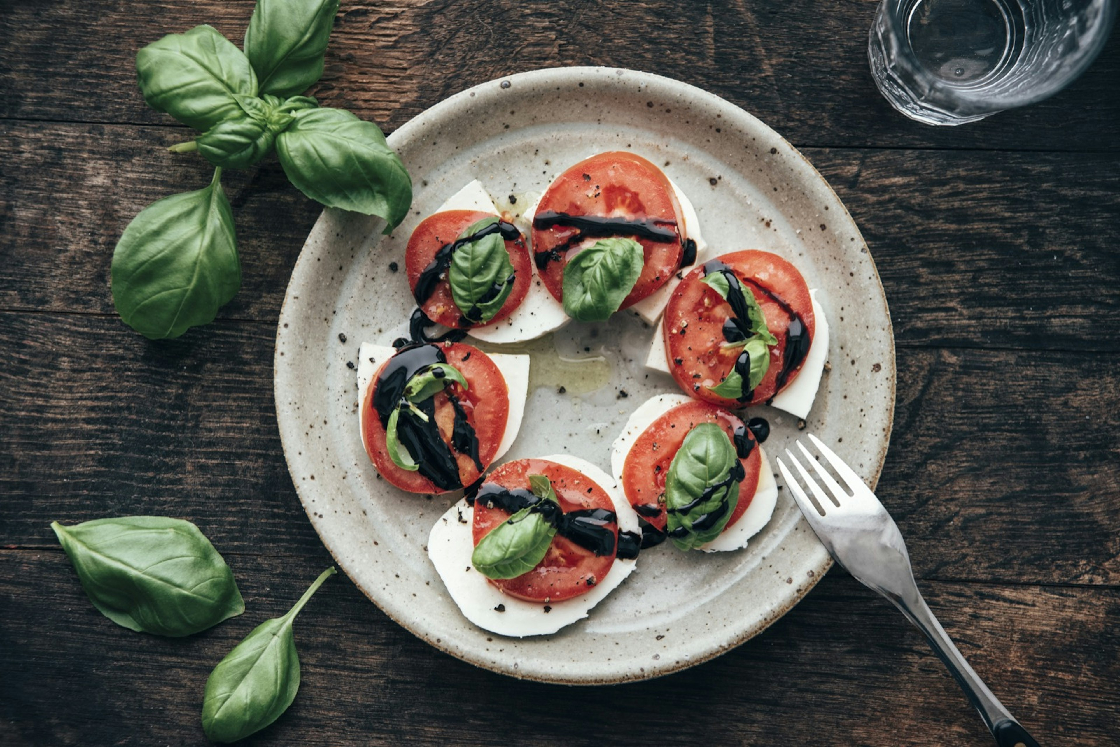 Overhead view of caprese salad with san marzano tomatos and mozzarella di buffala, all drizzled with basalmic vinegar; easy hostel meals