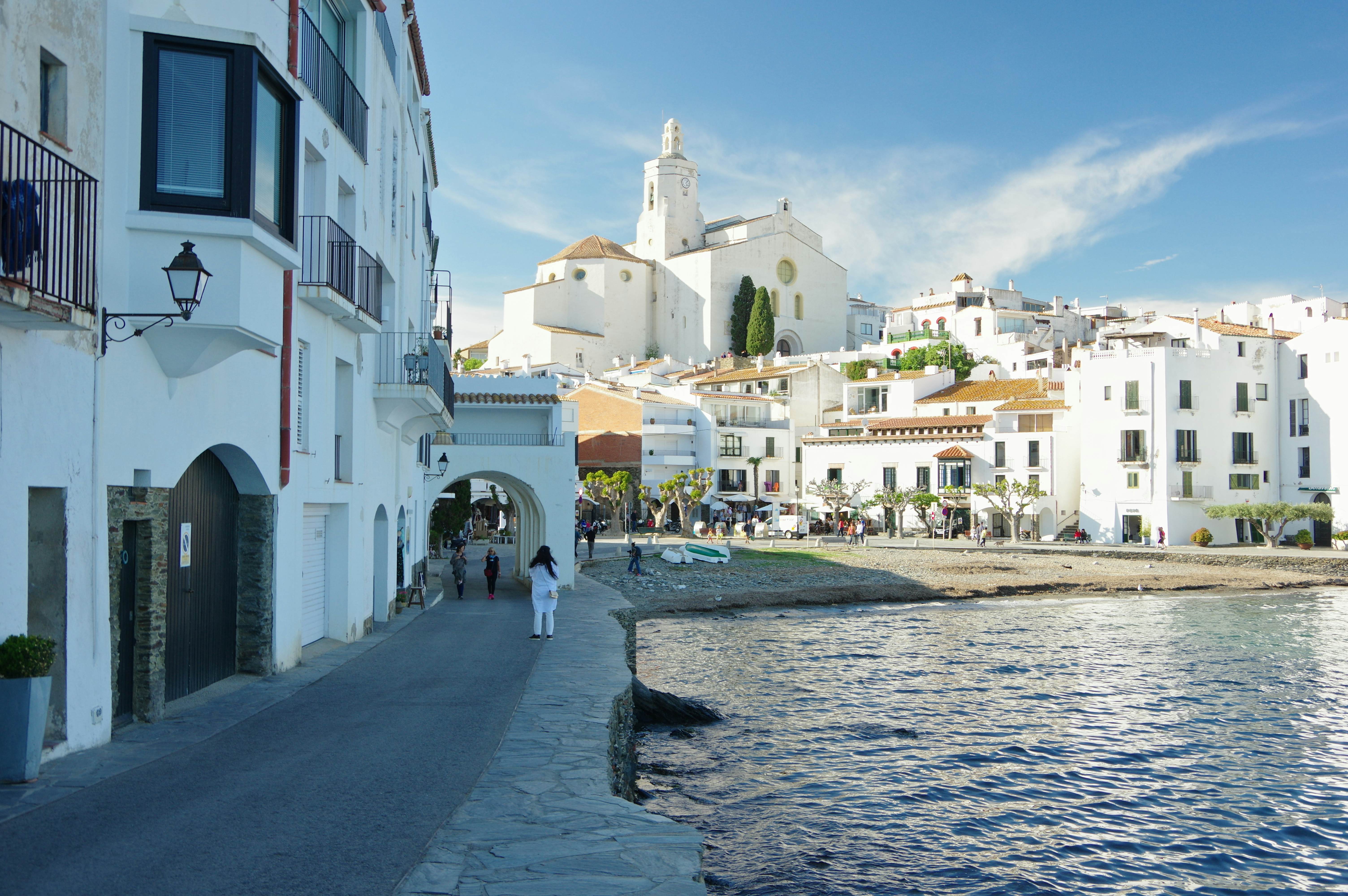 A person walks along the coast of a white-walled Spanish city.