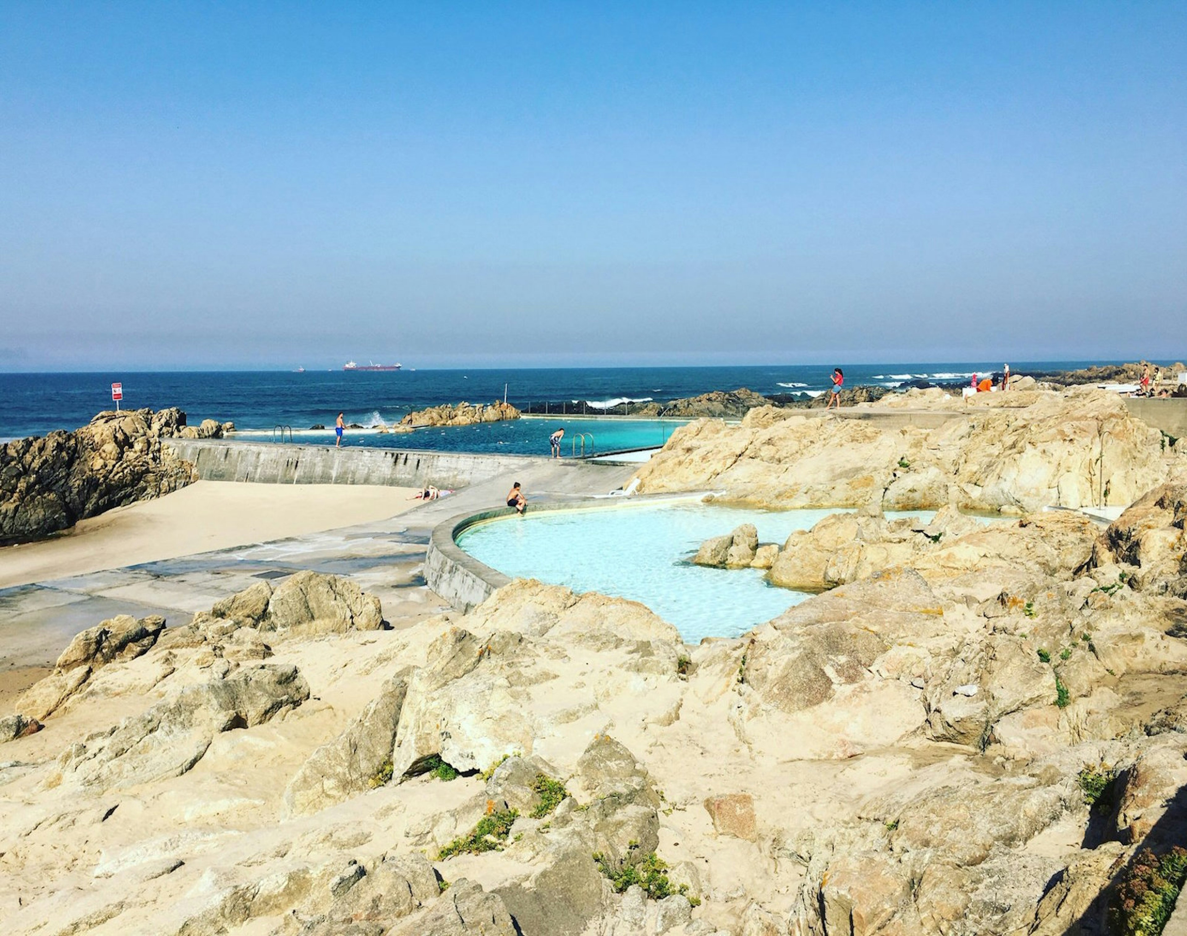 People swim in ocean-side pools formed in the rock