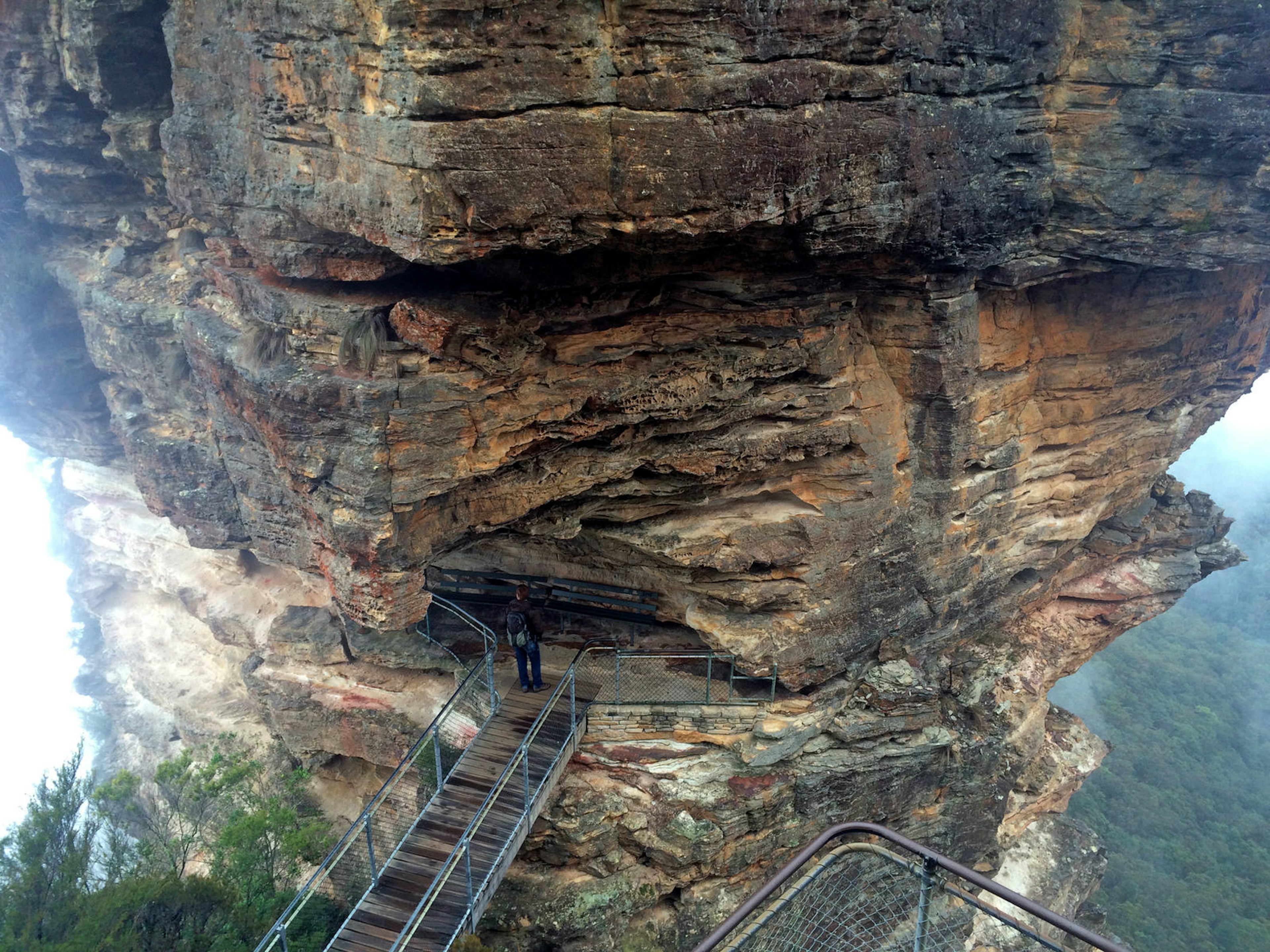 A hiker stands at the end of Honeymoon Bridge at base of the Three Sisters, a rock formation in the Blue Mountains National Park, New South Wales, Australia