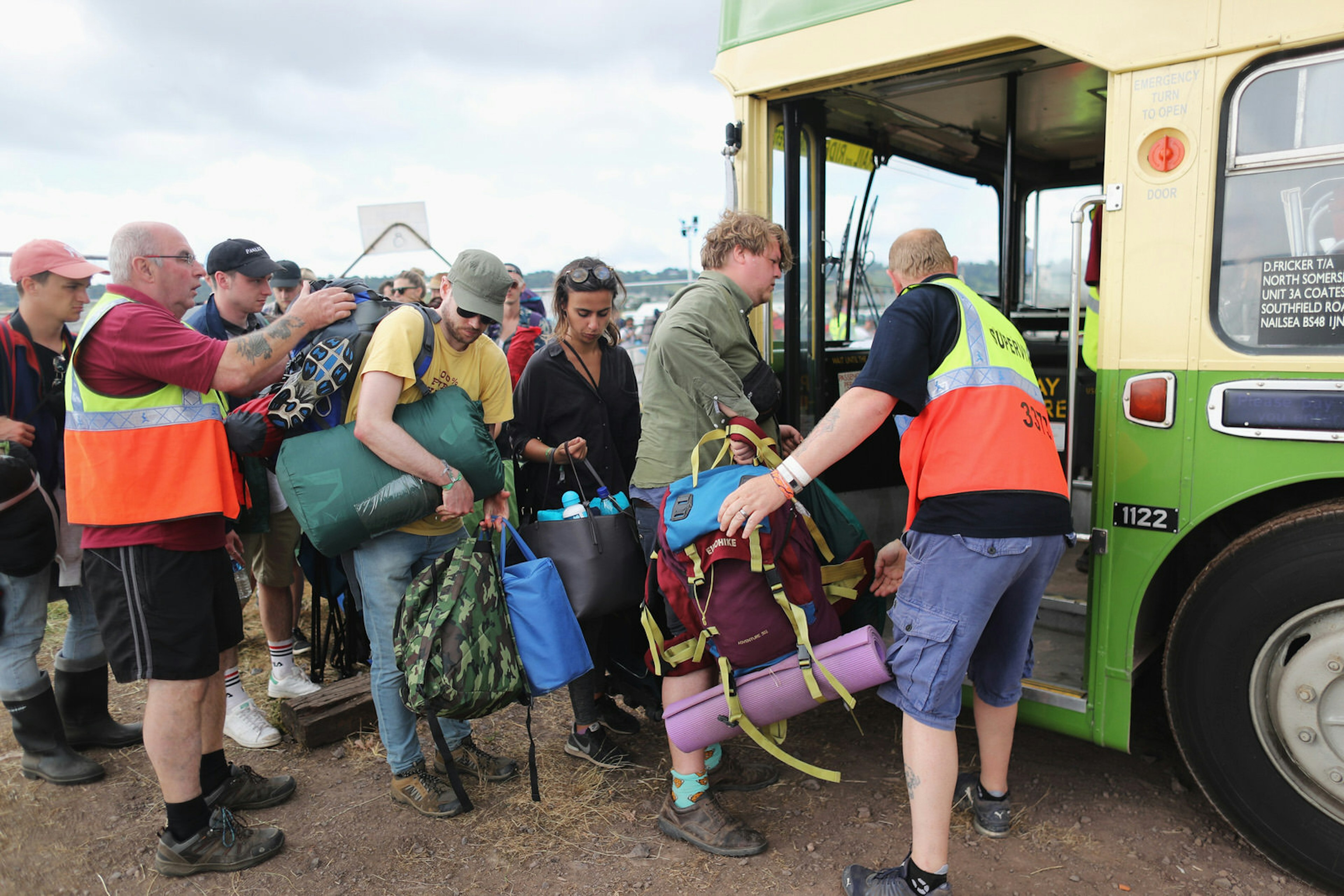 Festival goers are helped onto a bus by supervisors at the end of a music event