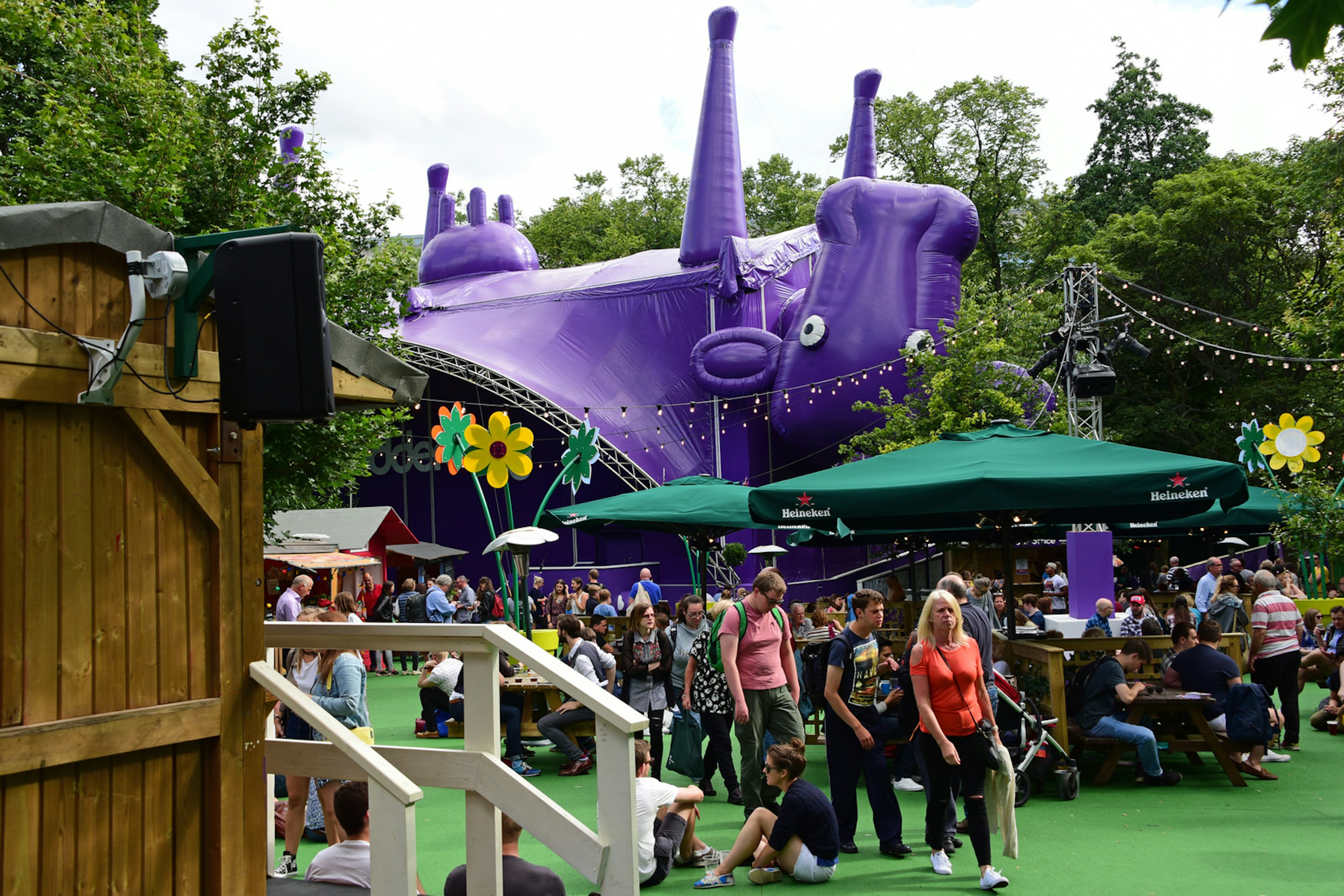 Fringe-goers enjoy the sunshine in the Underbelly Pasture, one of the off-street venues for the Edinburgh Festival Fringe. The Underbelly stage is a hug inflatable upside down purple cow.