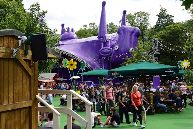 Fringe-goers enjoy the sunshine in the Underbelly Pasture, one of the off-street venues for the Edinburgh Festival Fringe. The Underbelly stage is a hug inflatable upside down purple cow.