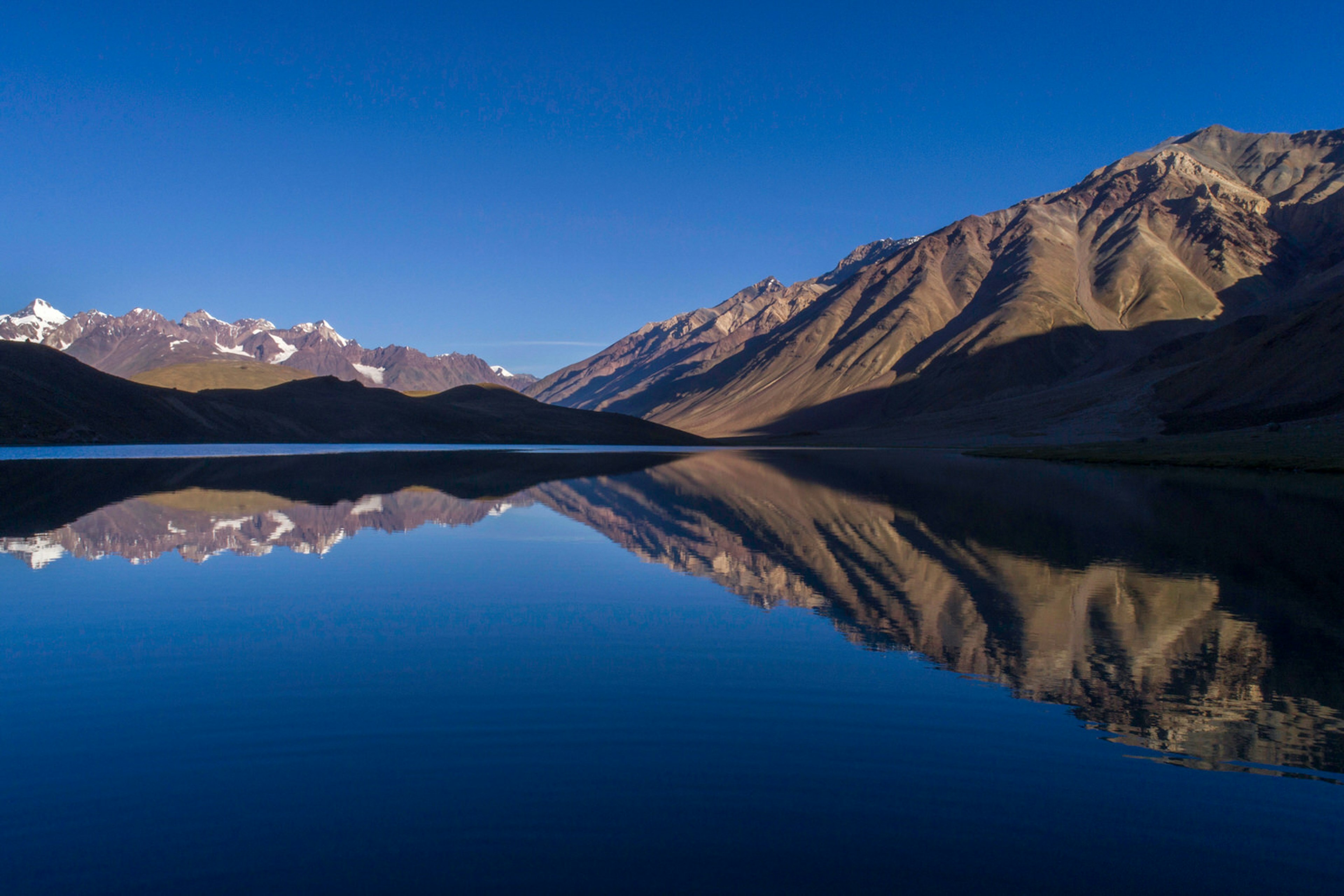 Chandratal Lake reflecting mountains on the horizon in Himachal Pradesh