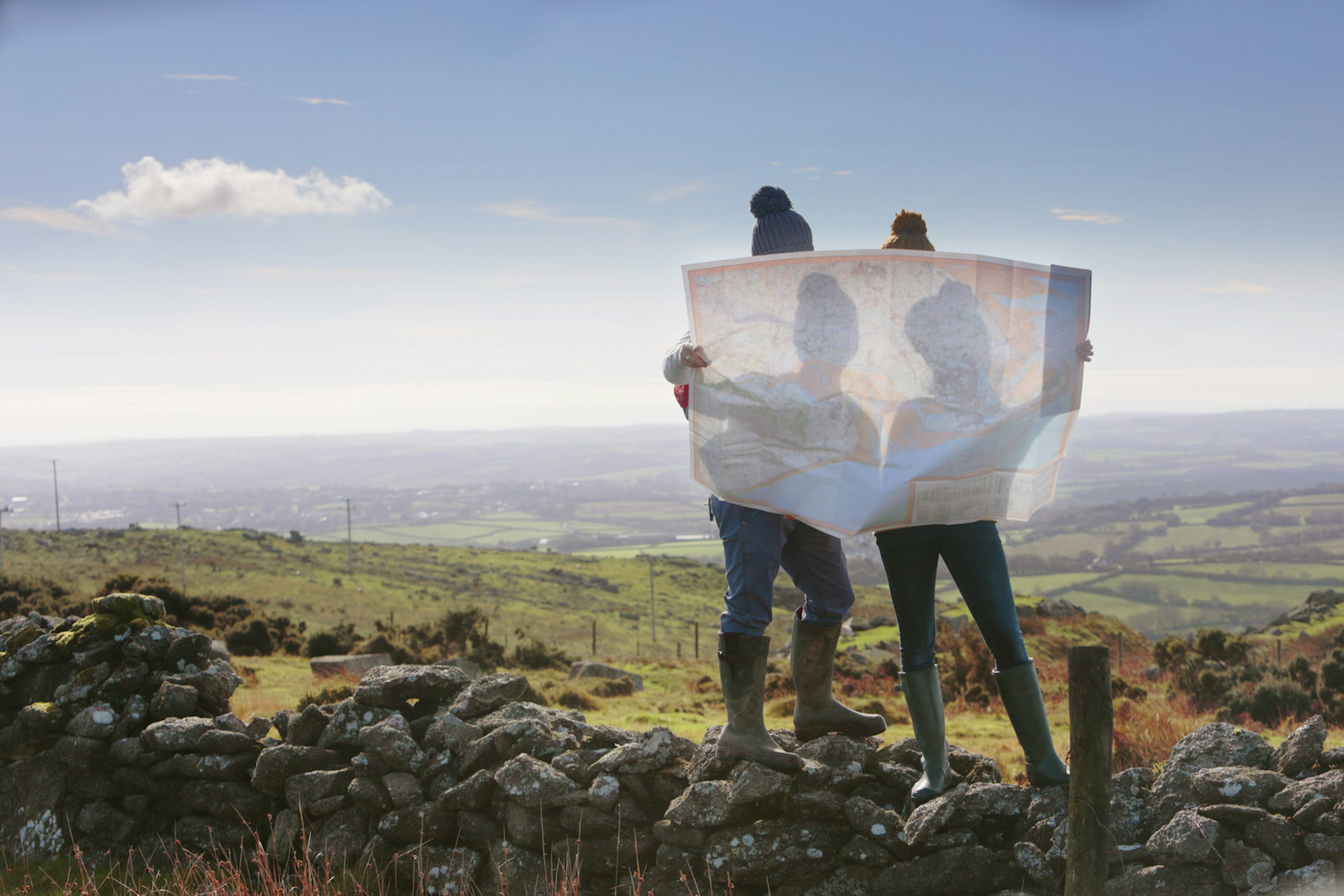 Two people read a map in welly boots in the countryside © Peter Cade / Getty Images