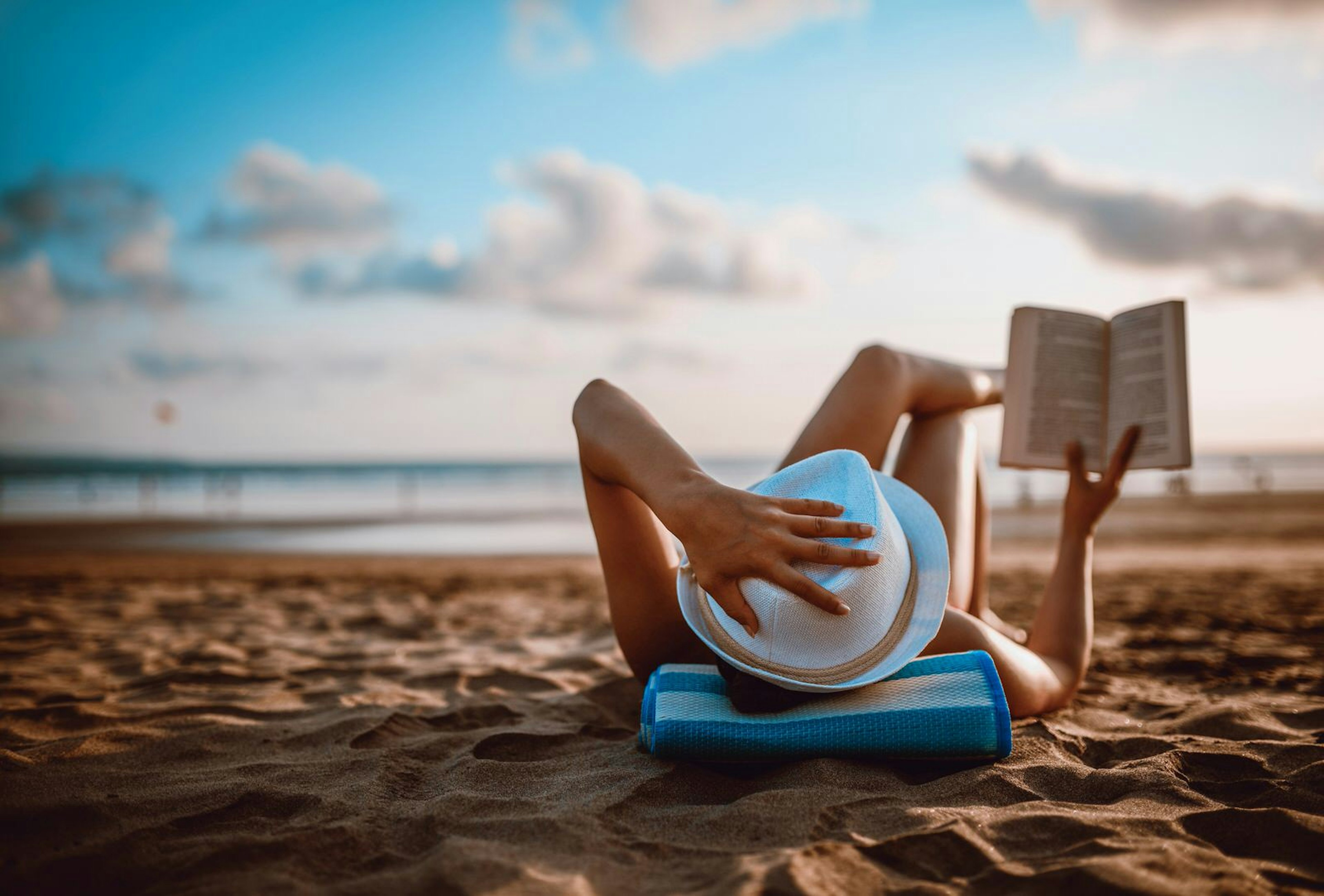 Female traveller reading on beach at sunset