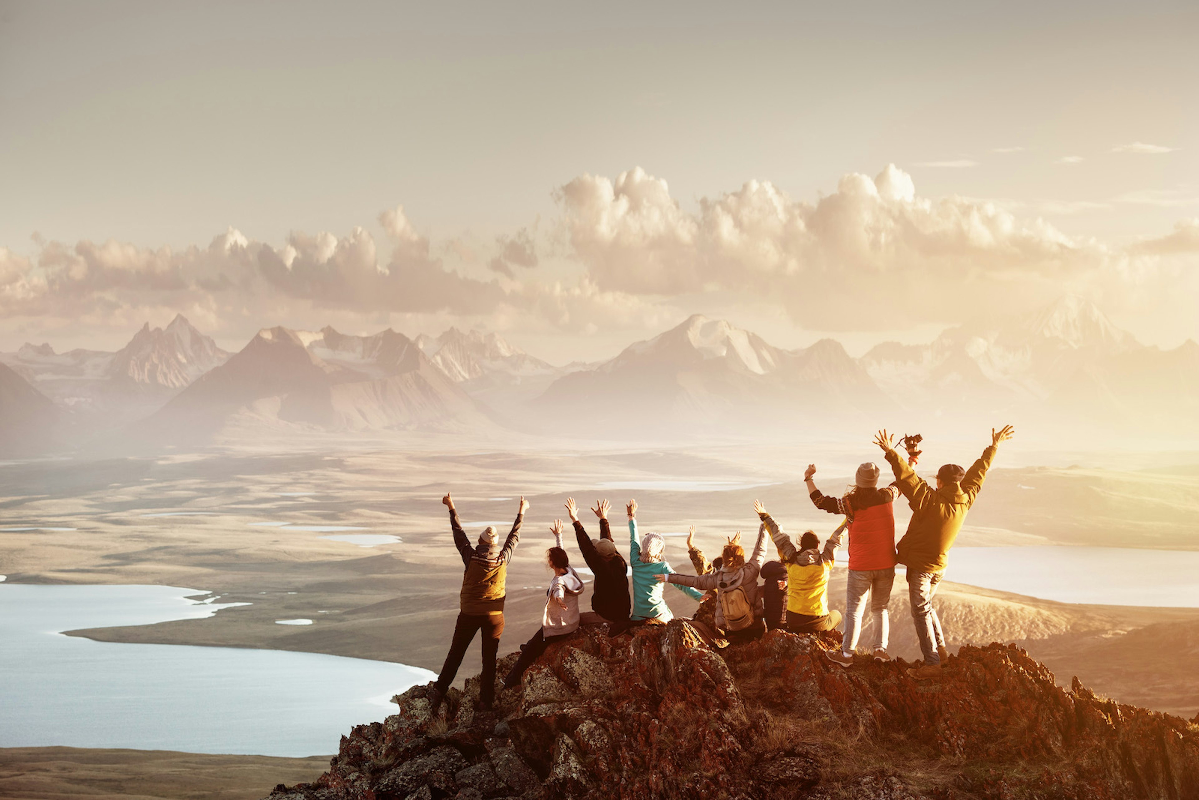 A group of people celebrate on the summit of a mountain