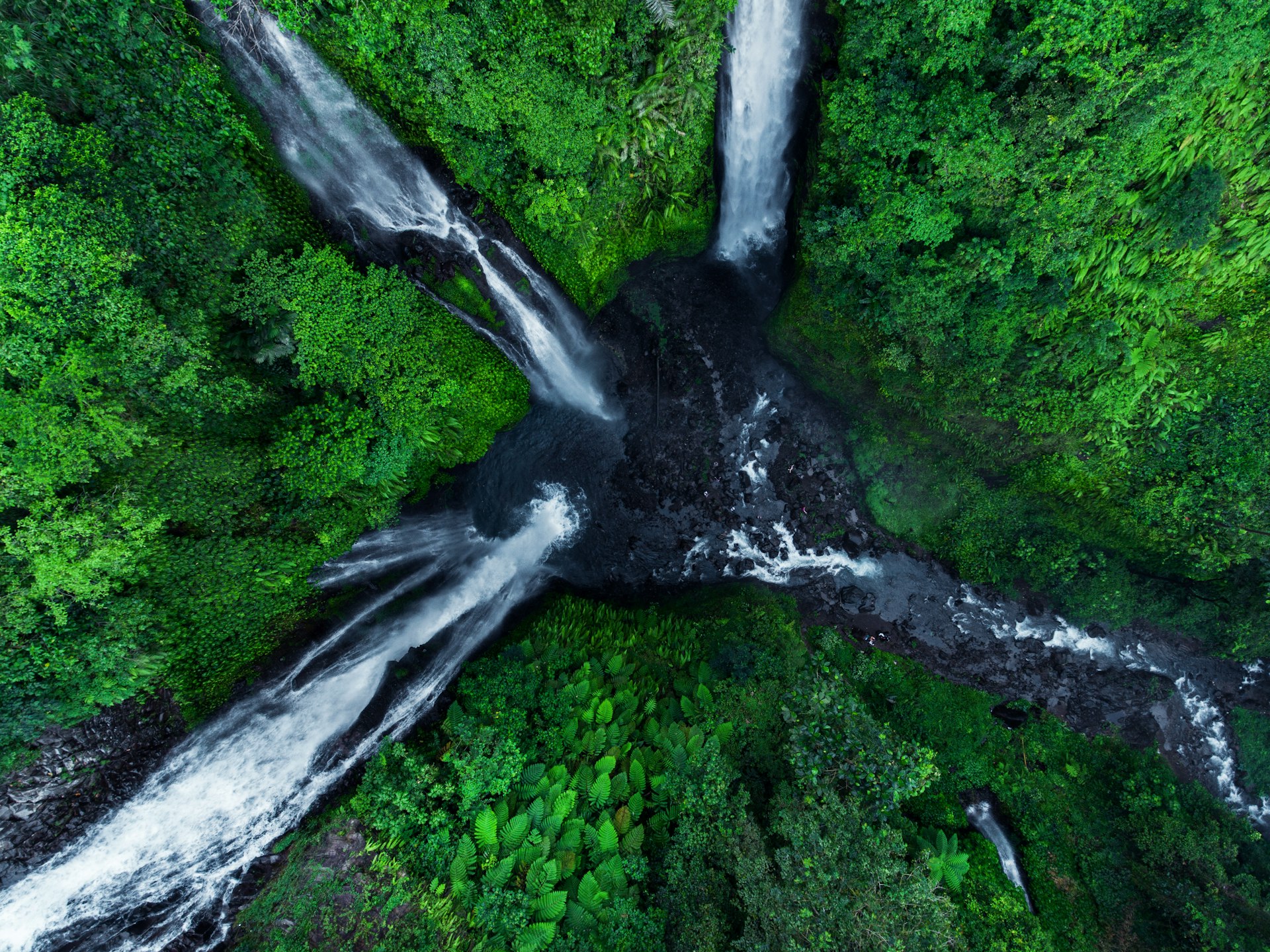 An overhead view of three waterfalls flowing the forest into one basin, Sekumpul, Bali