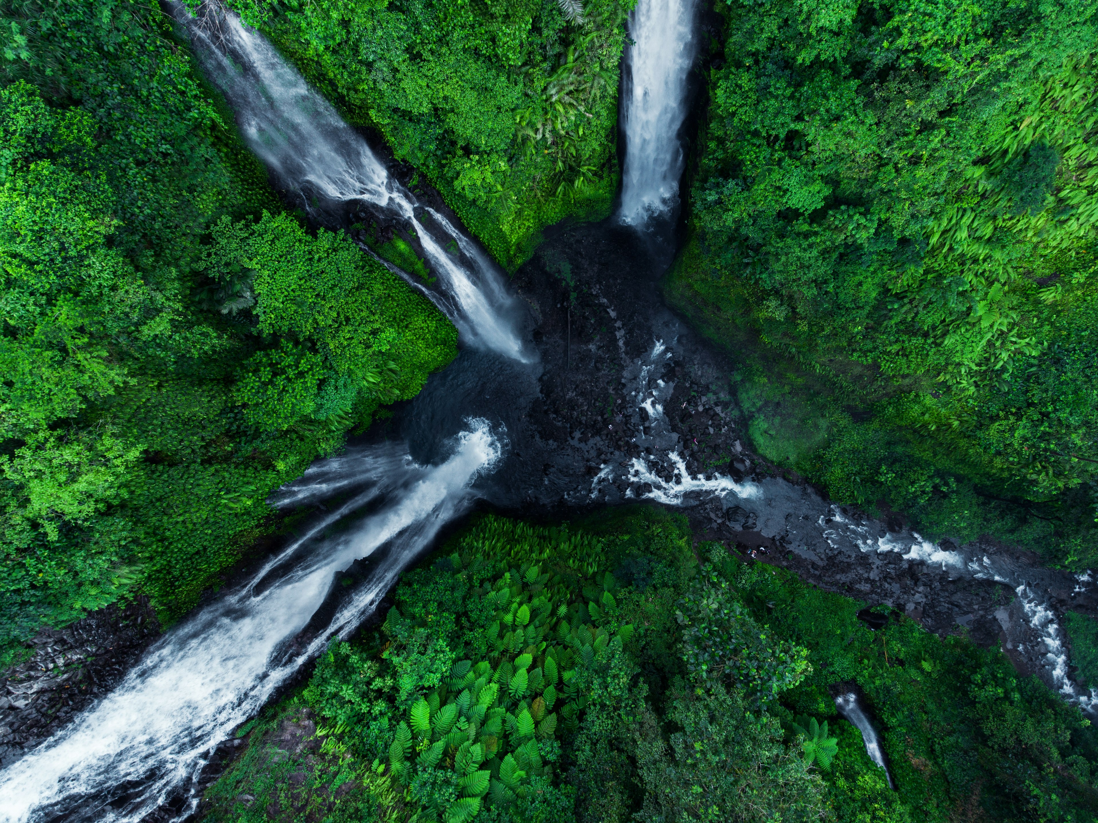 An overhead view of three waterfalls flowing the forest into one basin, Sekumpul, Bali