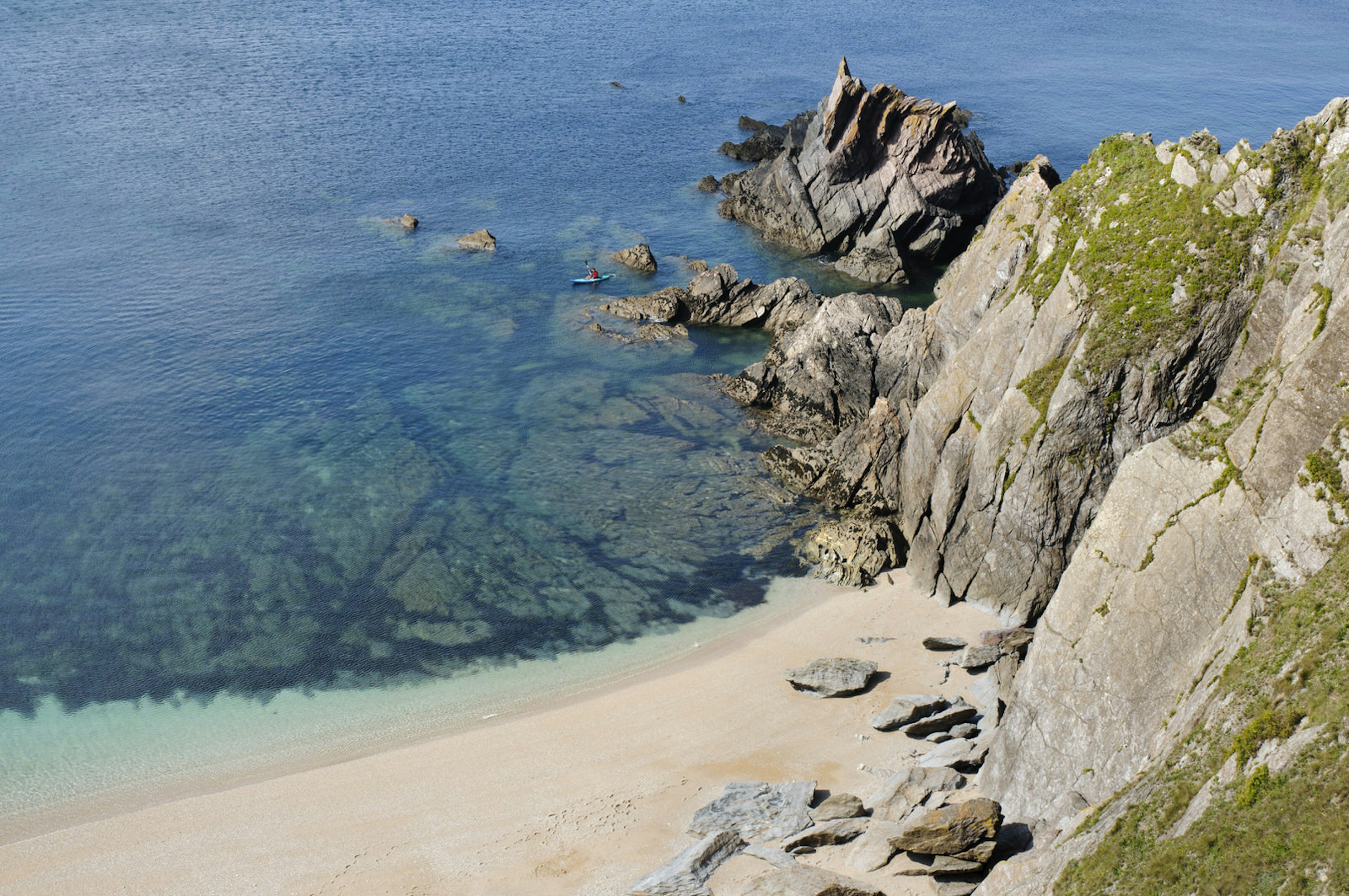 A beautiful beach backed by steep cliffs in south Devon, England, with small sea kayak visible © threeseven / Getty Images