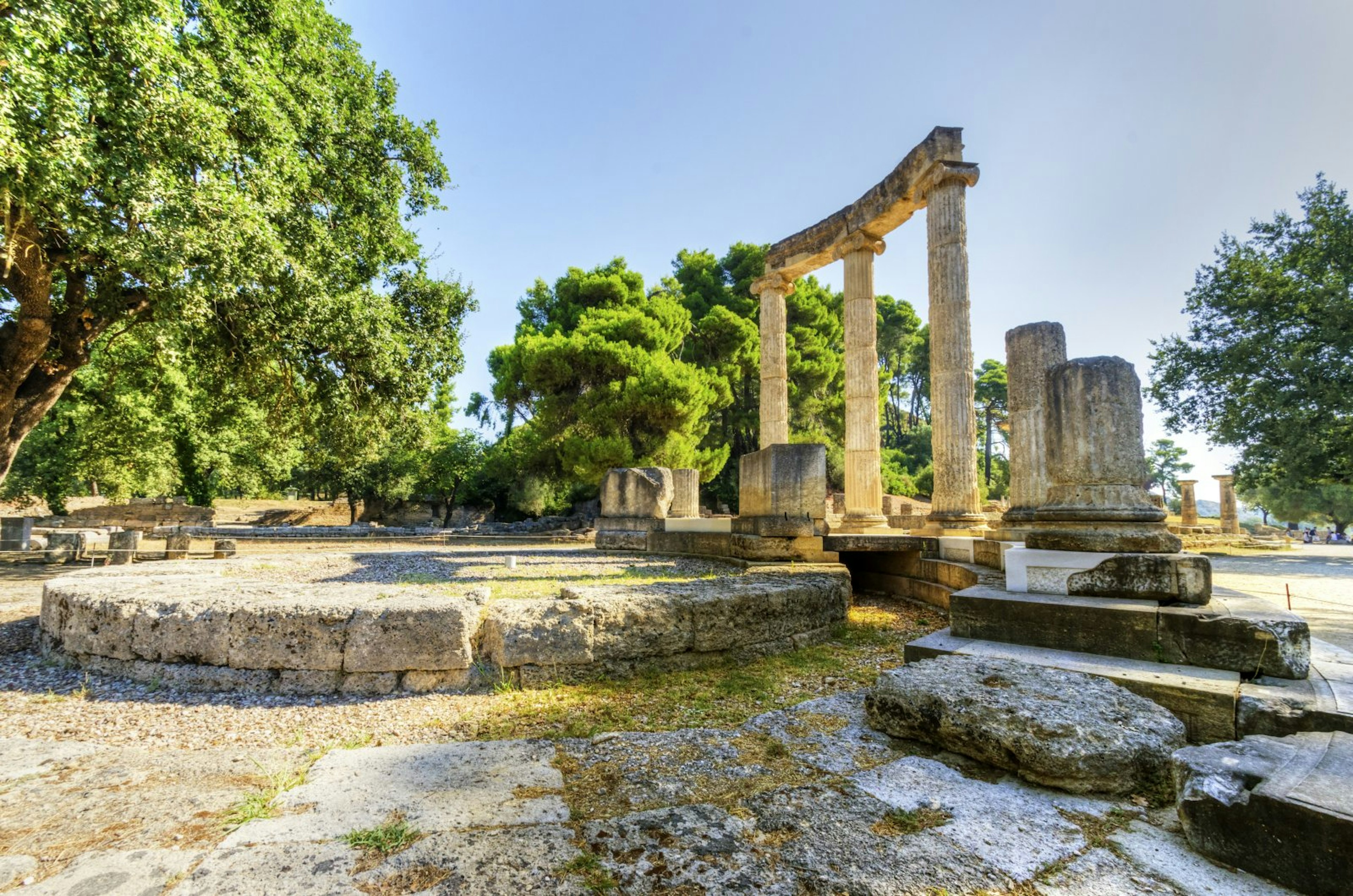 Three columns stand intact, with several ruined columns around