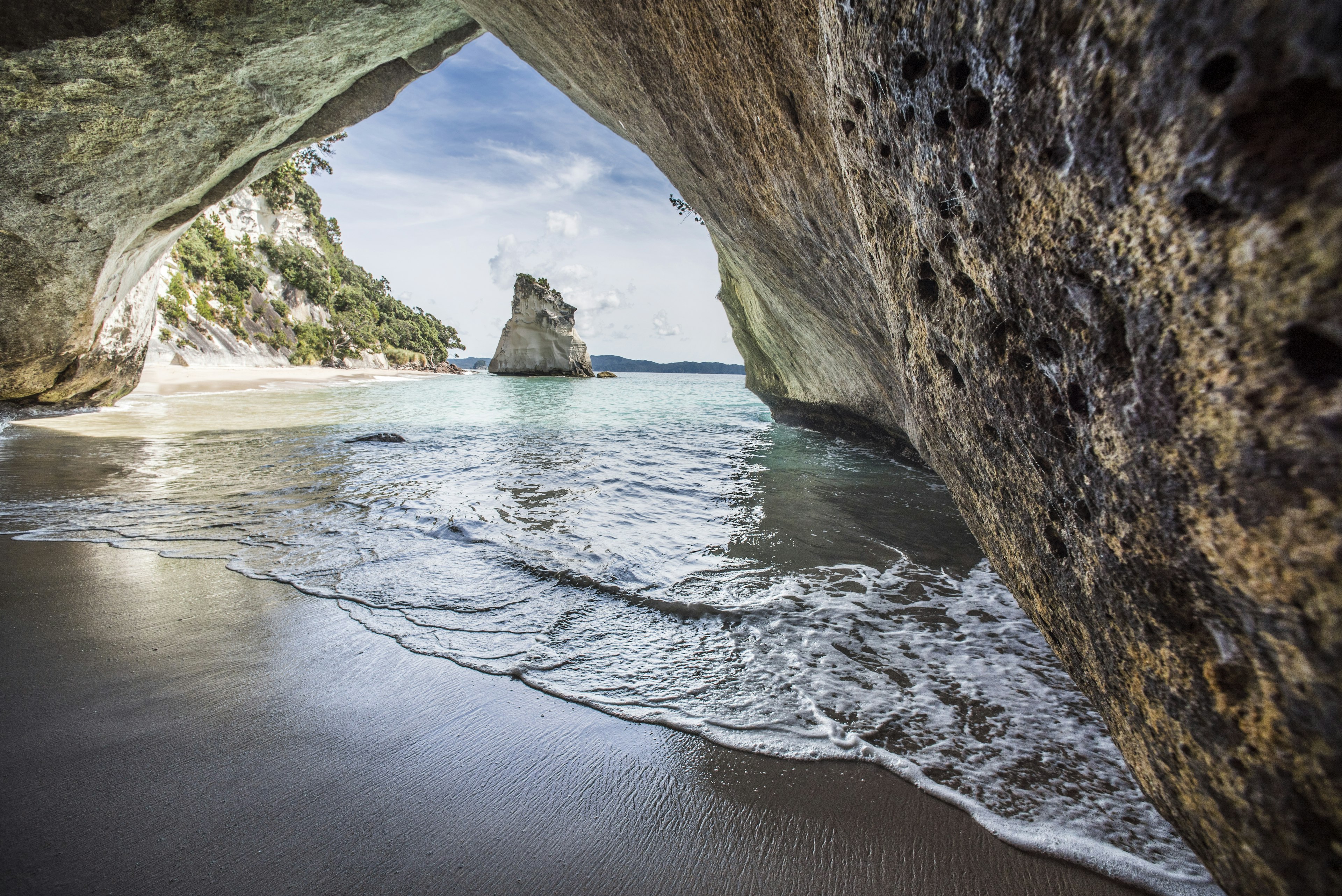 A large rock islet at the edge of a beach