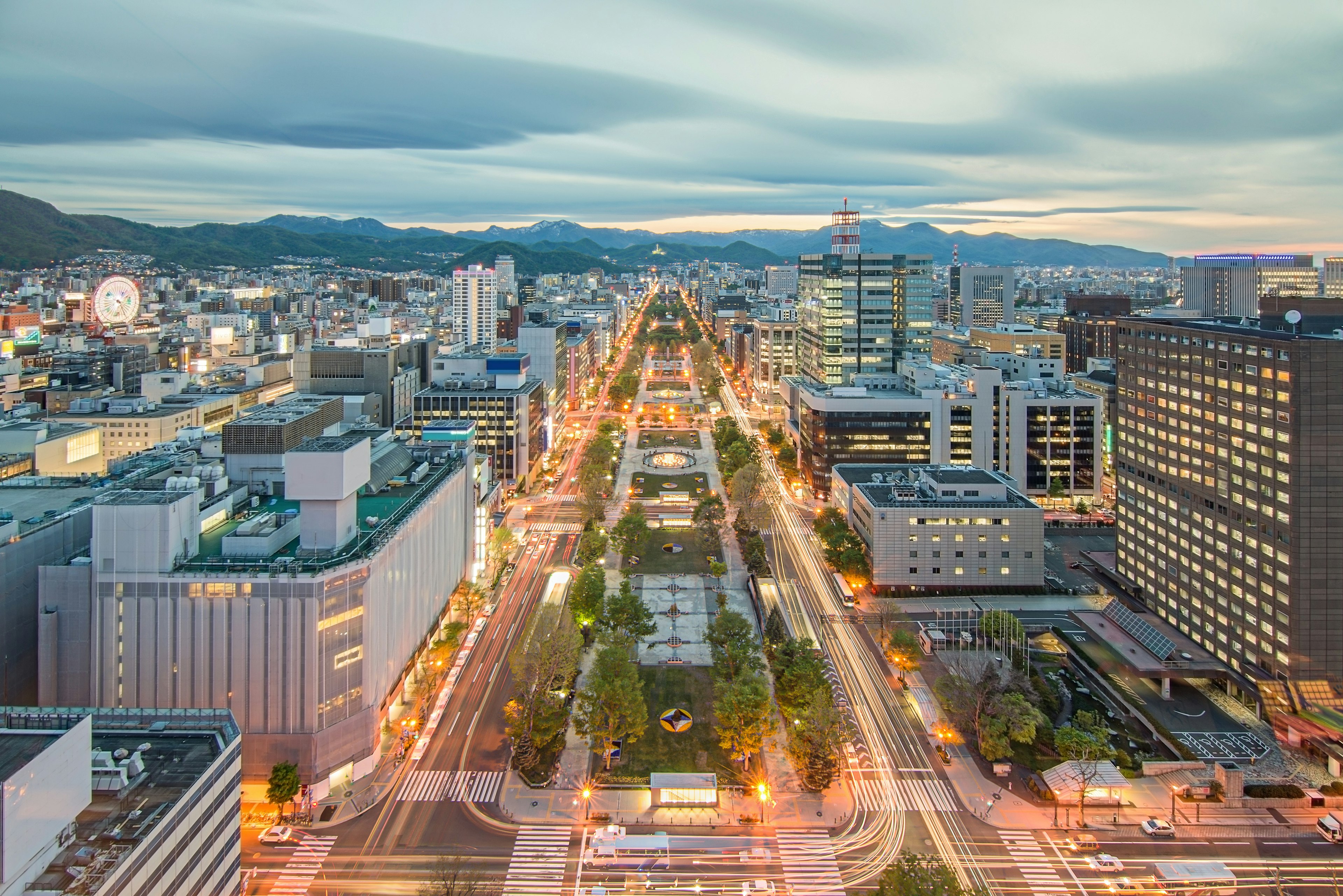 Overhead shot of city streets, with mountains in the distance and clouds above