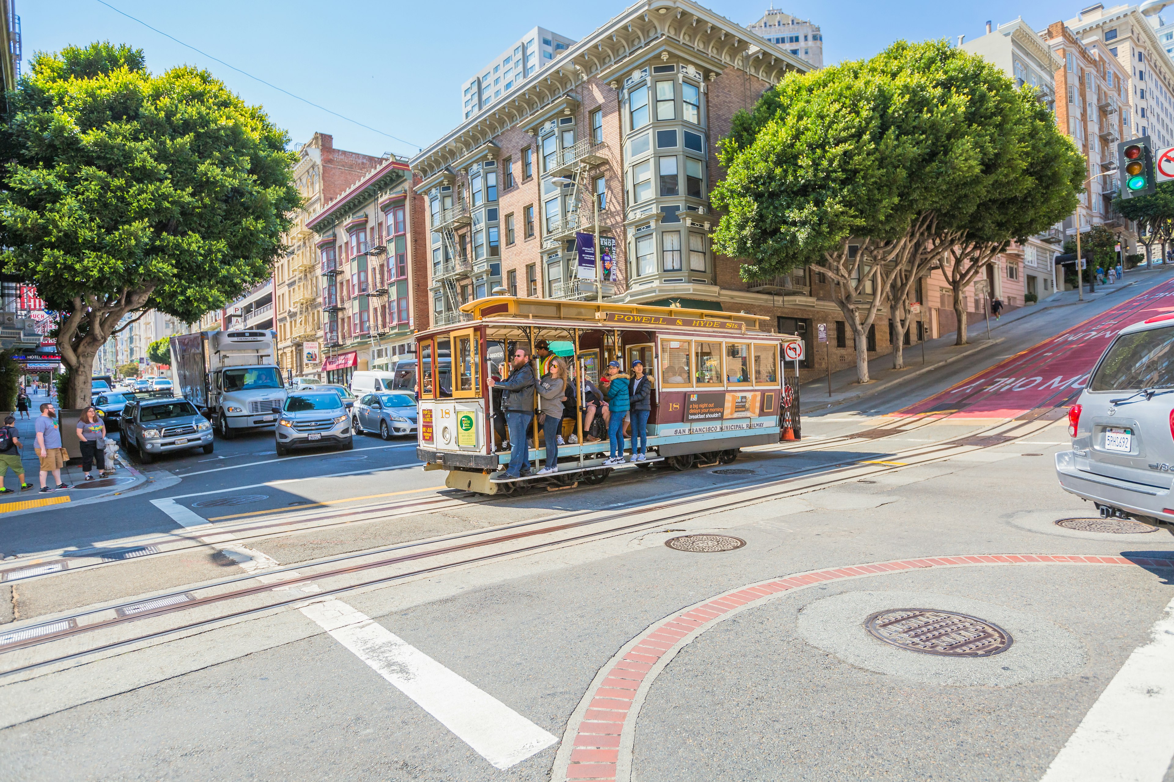 A cable car loaded with passengers crosses a major road junction on a sunny day