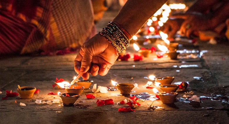 Close-up of a hand lighting incense on the ground at night in Varanasi.
758617141
Human Hand, Varanasi, Color Image, Focus, Celebration, India, Real People, Adults Only, Illumination, Photography, Image Focus Technique, People, Part Of, One Woman Only, Horizontal, Holding, Only Women, Hold, Adult, Human Body Part, Glowing, Selective Focus, Oil Lamp, Close-up, Diwali, Street, Women, Bracelet, Spirituality, Diya - Oil Lamp, Religion, Petal, One Person, Flame, Heat - Temperature, Candle, Illuminated, Lifestyles, Outdoors, Burning, Night