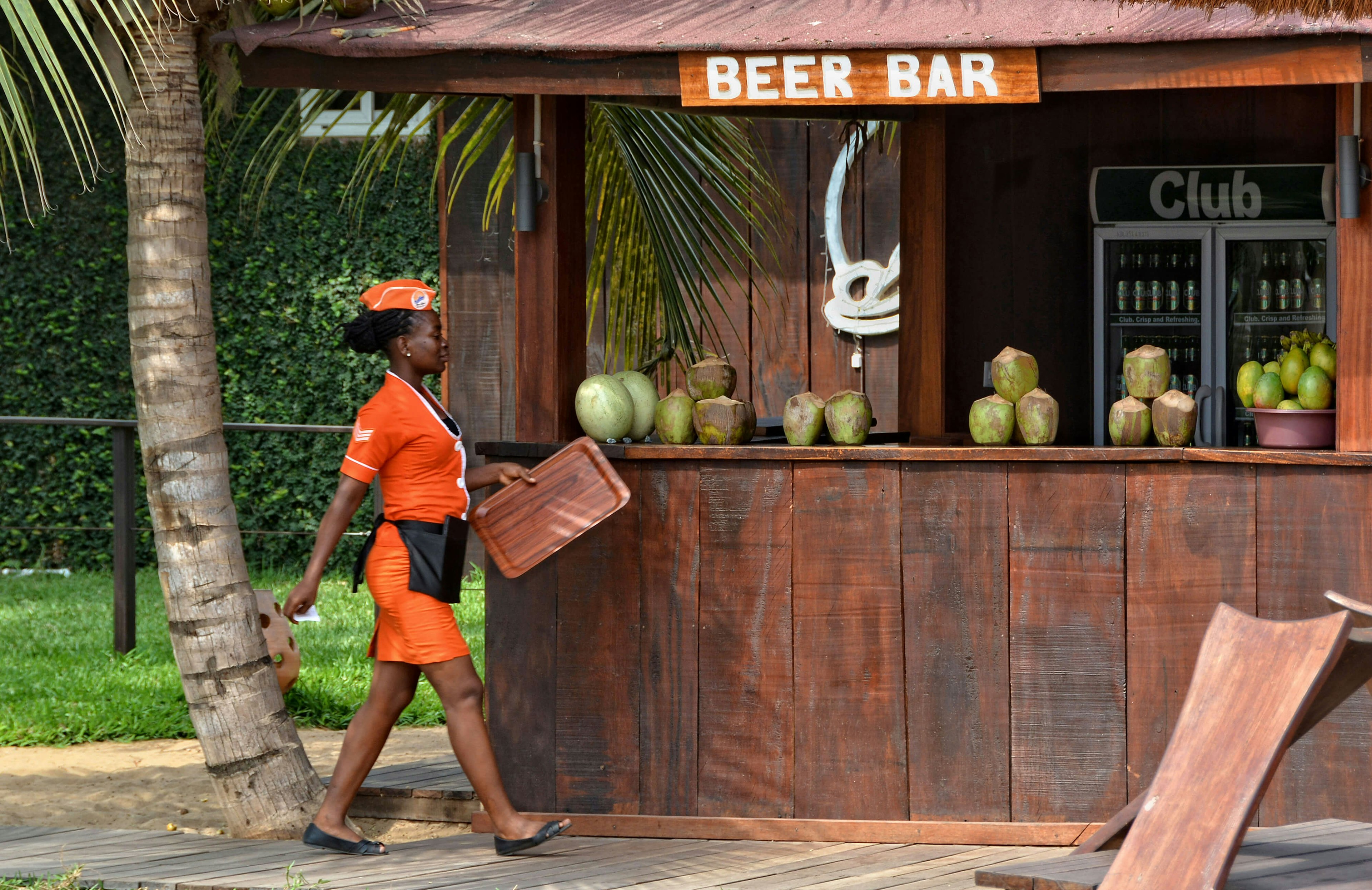 Waitress and an African open-air bar with coconuts and beer. Travel and vacation in West Africa. Aqua Safari Resort.