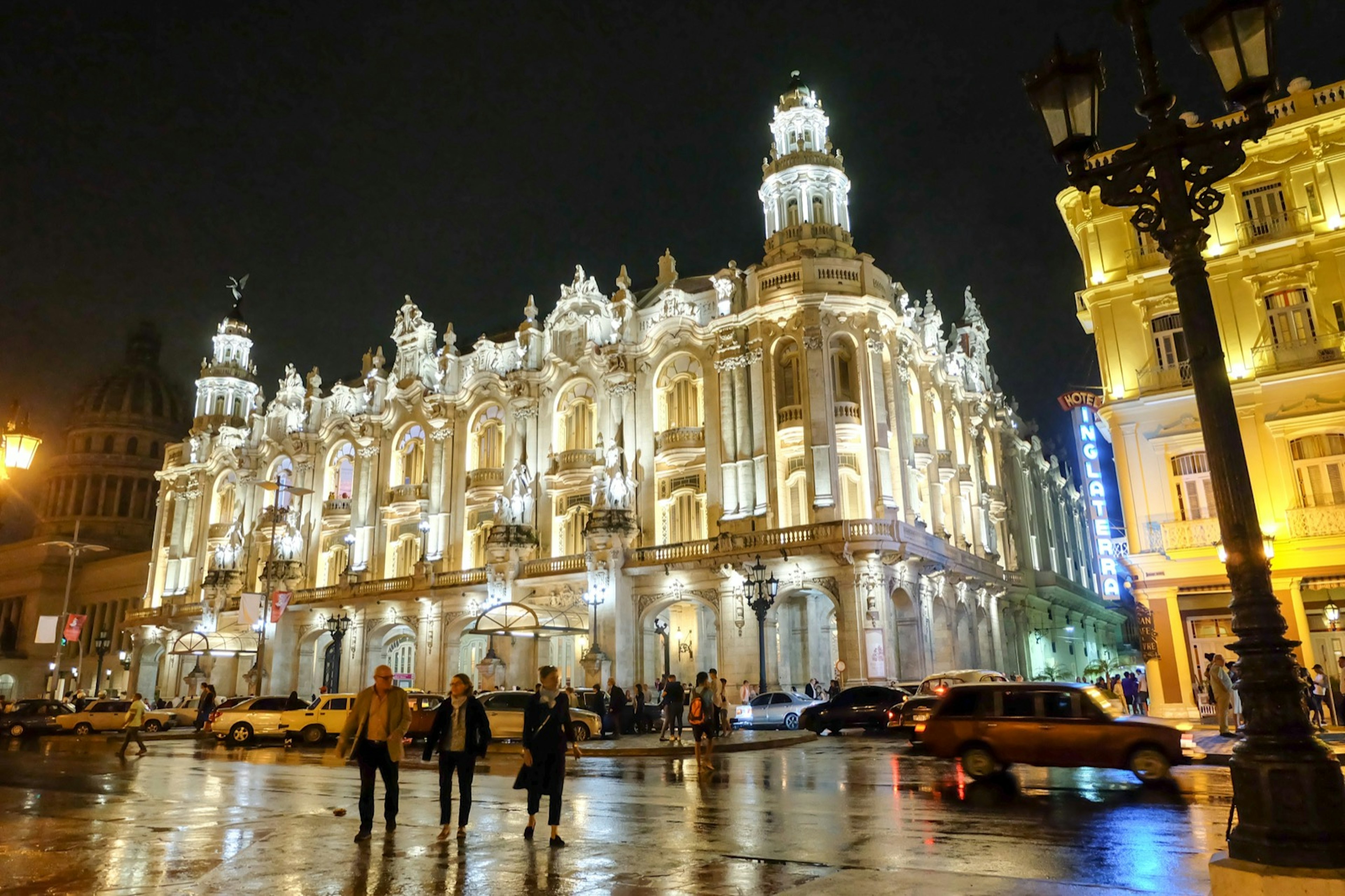 A trio of people walk in front of the illuminated Gran Teatro de la Habana Alicia Alonso in Havana at night © Diana Rita Cabrera / ϰϲʿ¼