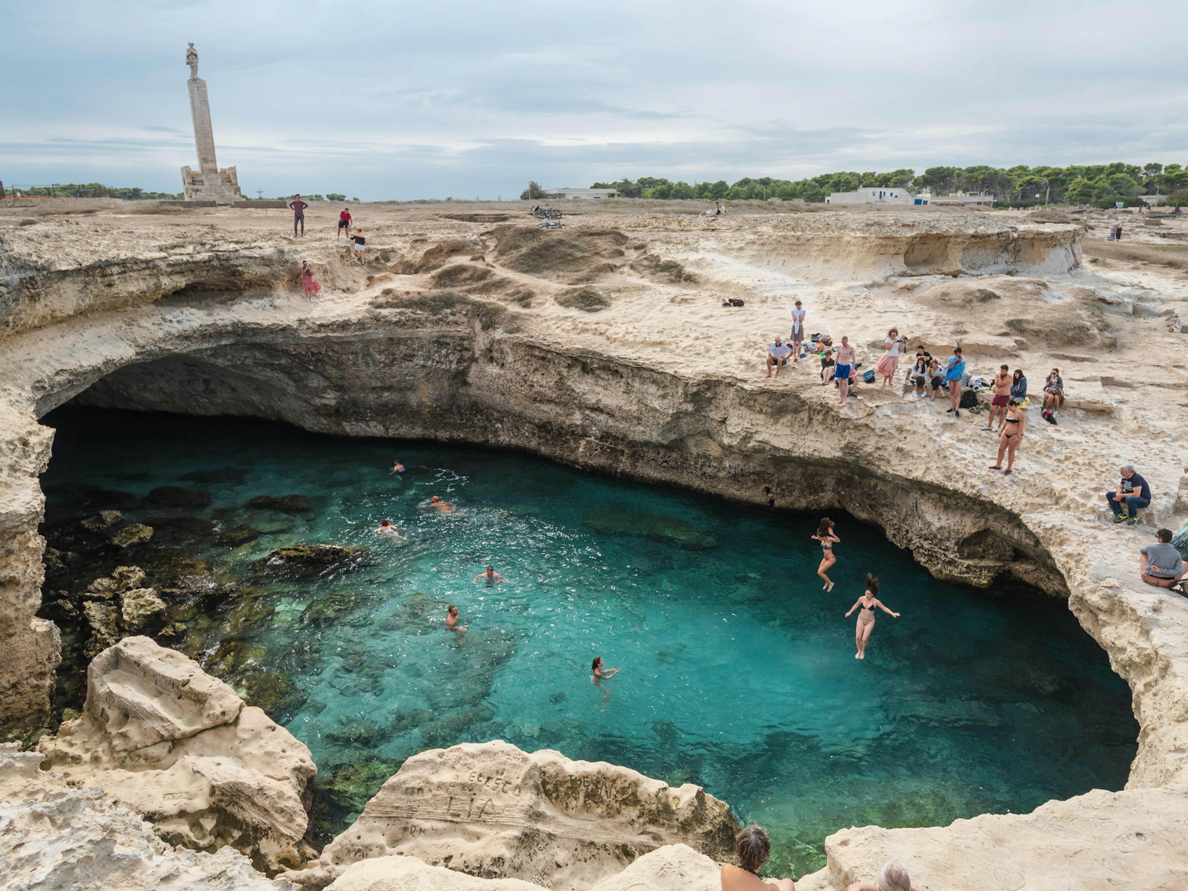 People jumping into the a grotto filled with seawater