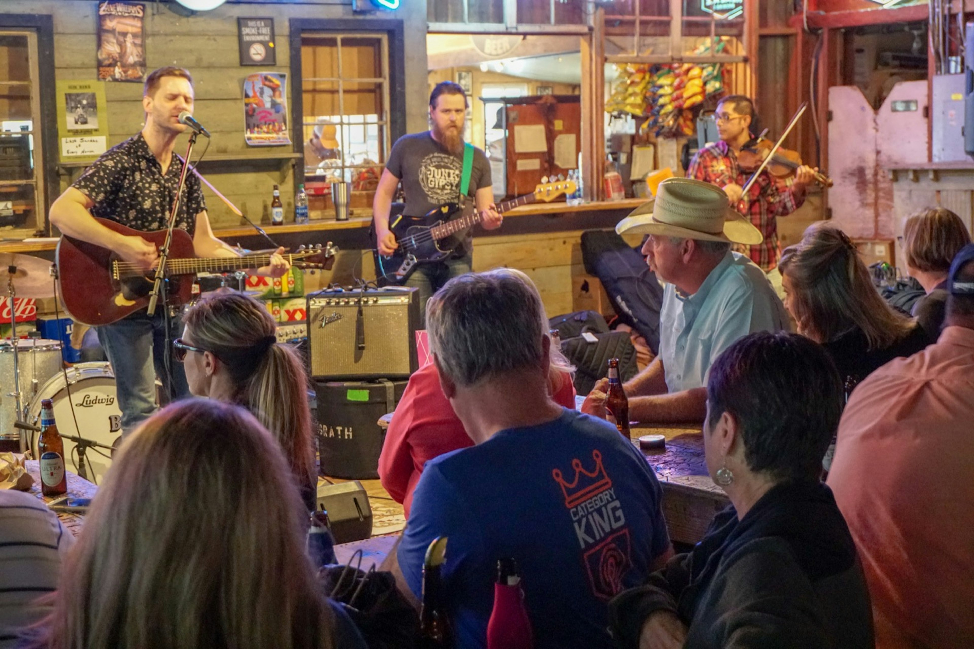 Rows of tables filled with people sitting very close to a small band performing in an indoor dance hall in the Hill Country