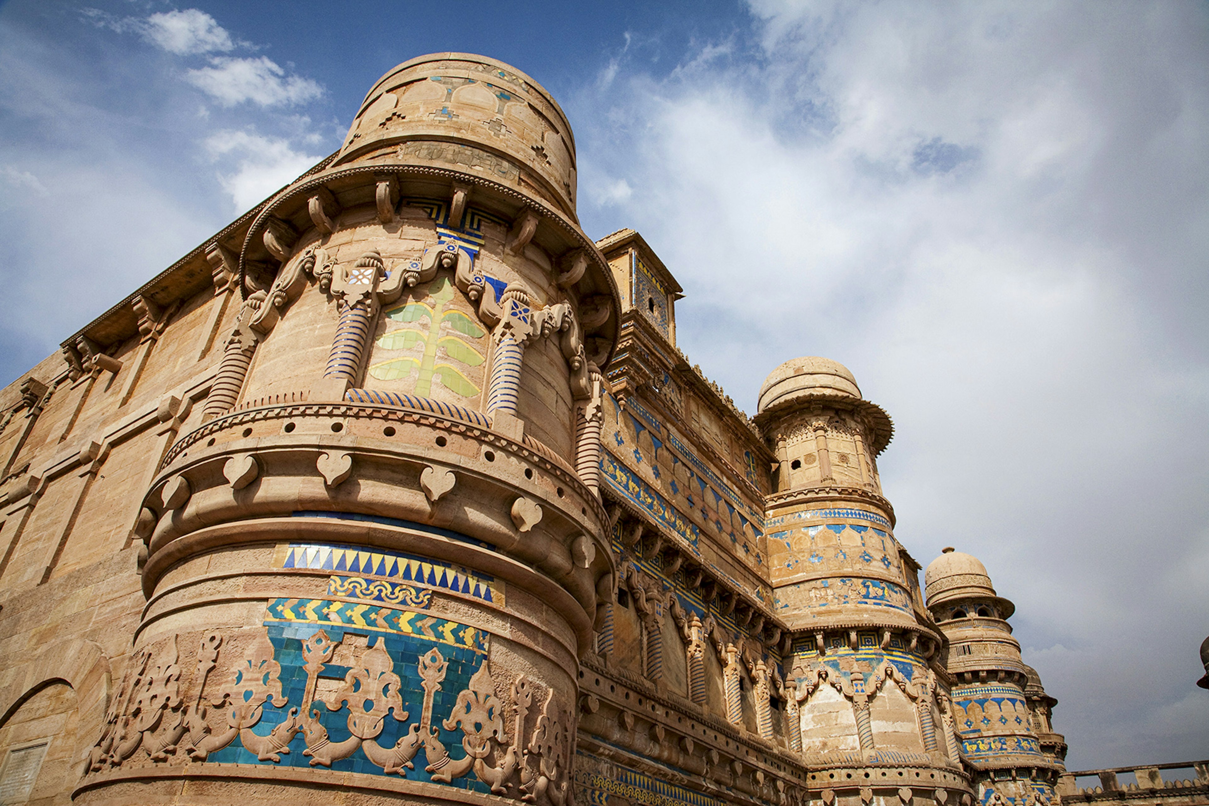 A close image of Gwalior's battlements covered in carvings and blue tile, and topped with rounded turrets. Madhya Pradesh, India.