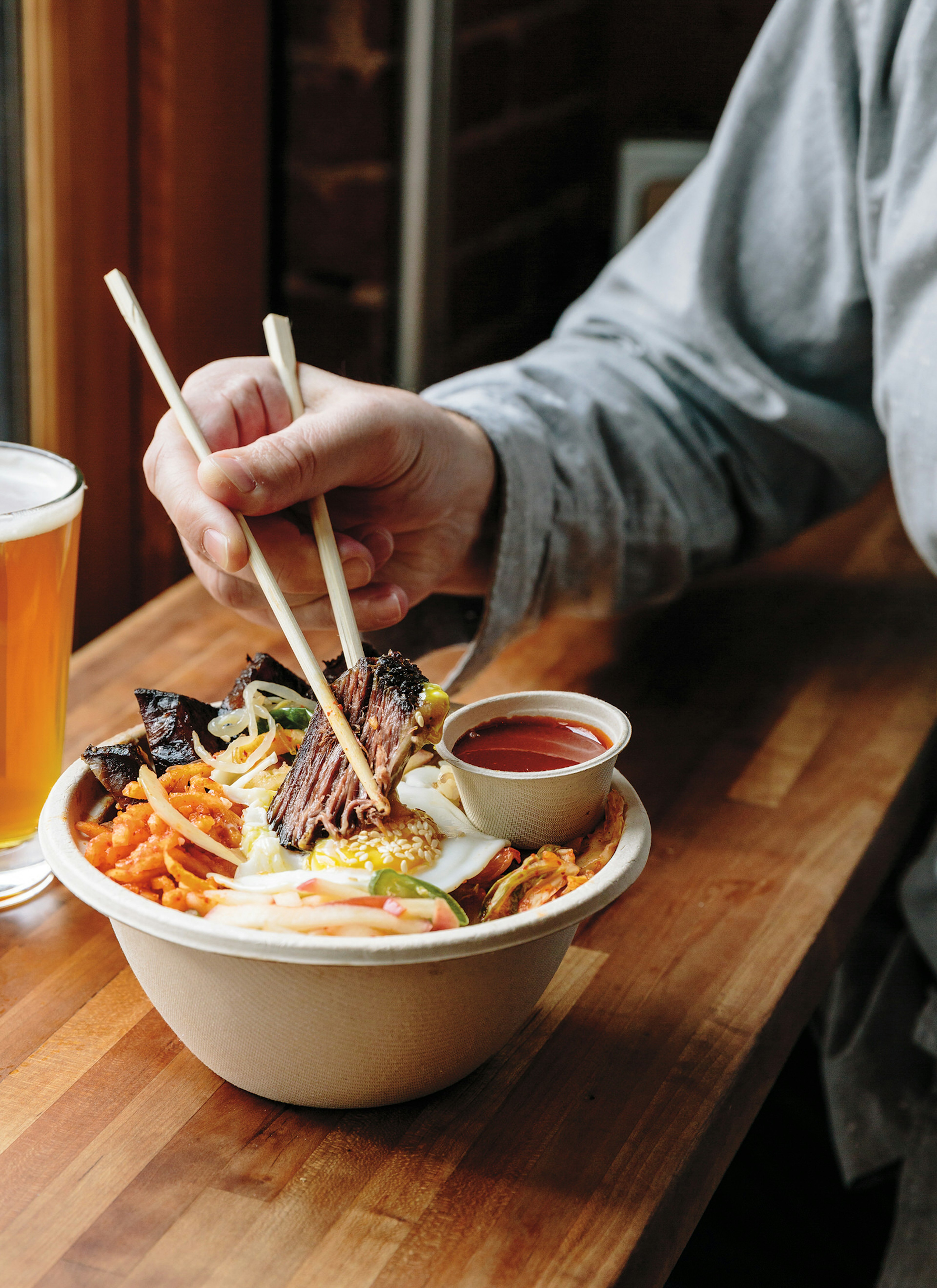 Short rib bibimbap bowl with a beer at Kim Jong Smokehouse © Alanna Hale / Lonely Planet