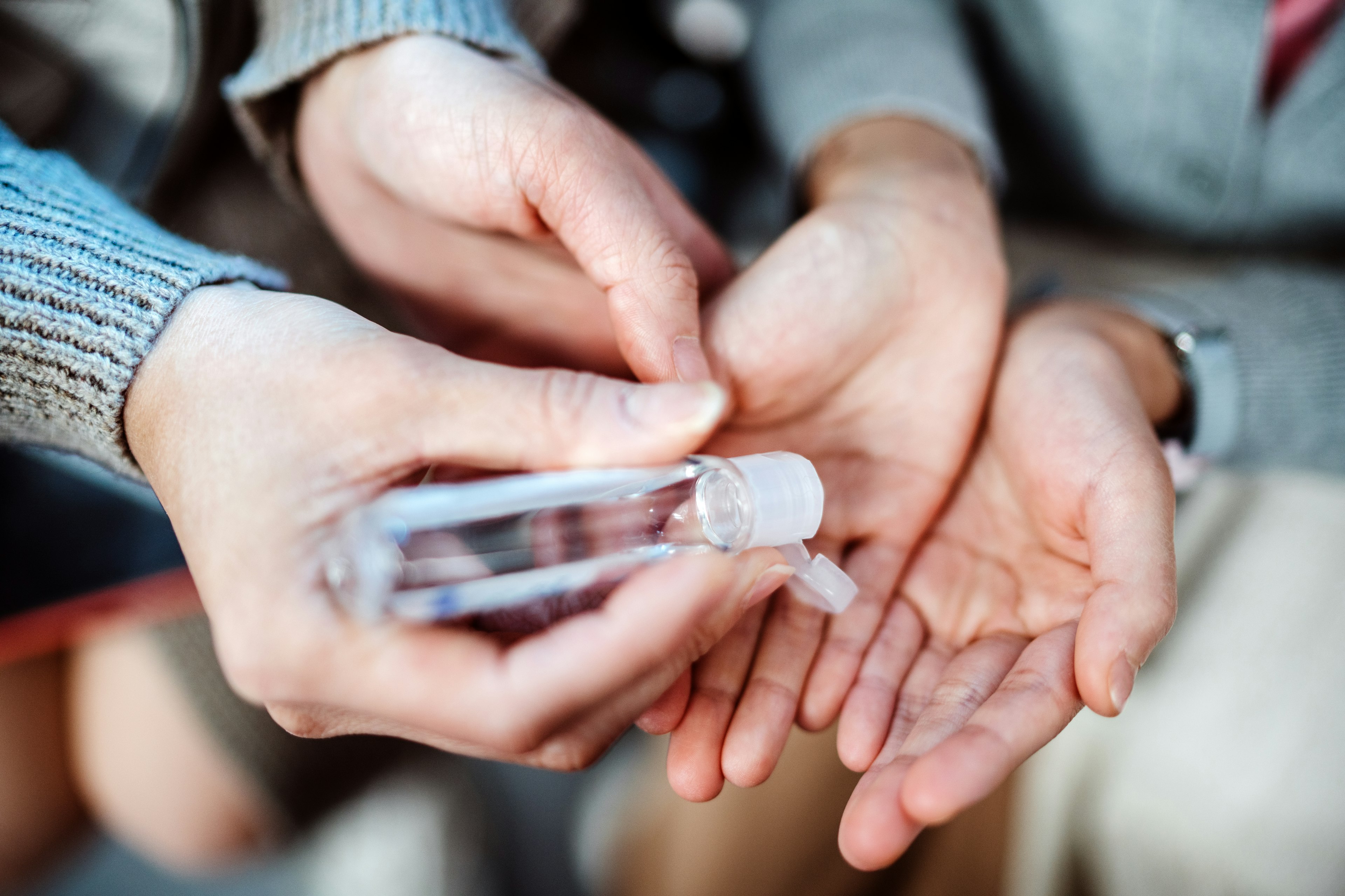 Adult squeezing hand sanitizer onto child's hands