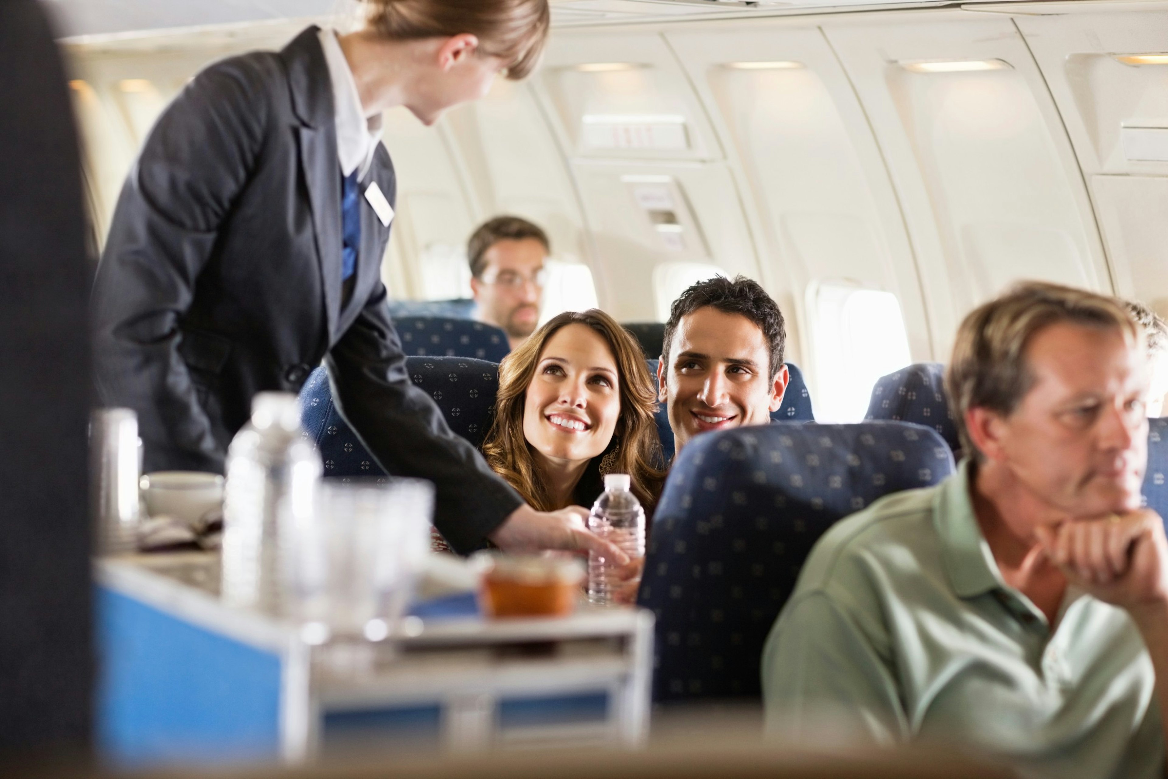 A flight attendant serving customers on an airplane