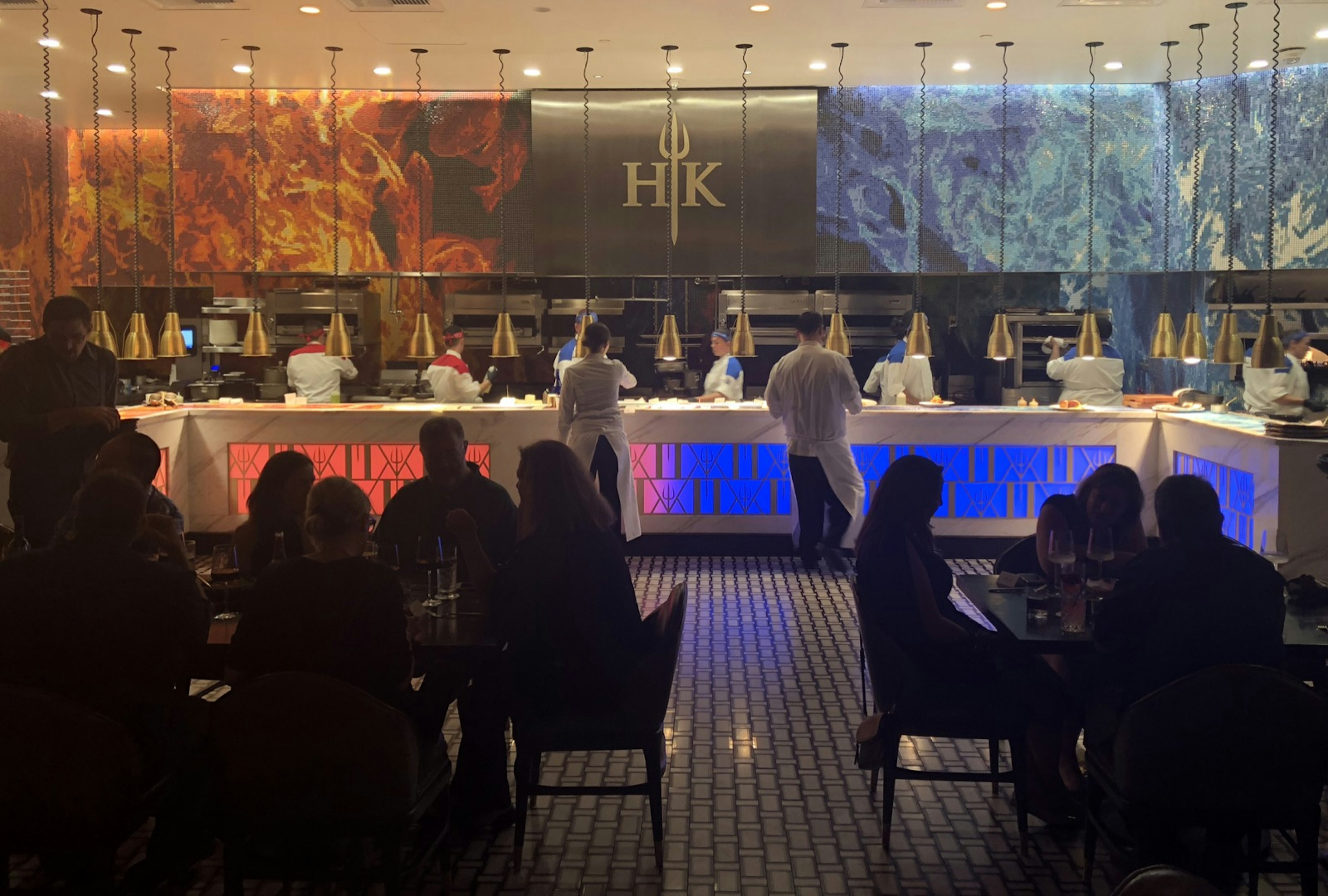 Red and blue flames mark a mural above a long kitchen as diners sit in the dark and waiters move back and forth at a celebrity chef restaurant in Las Vegas