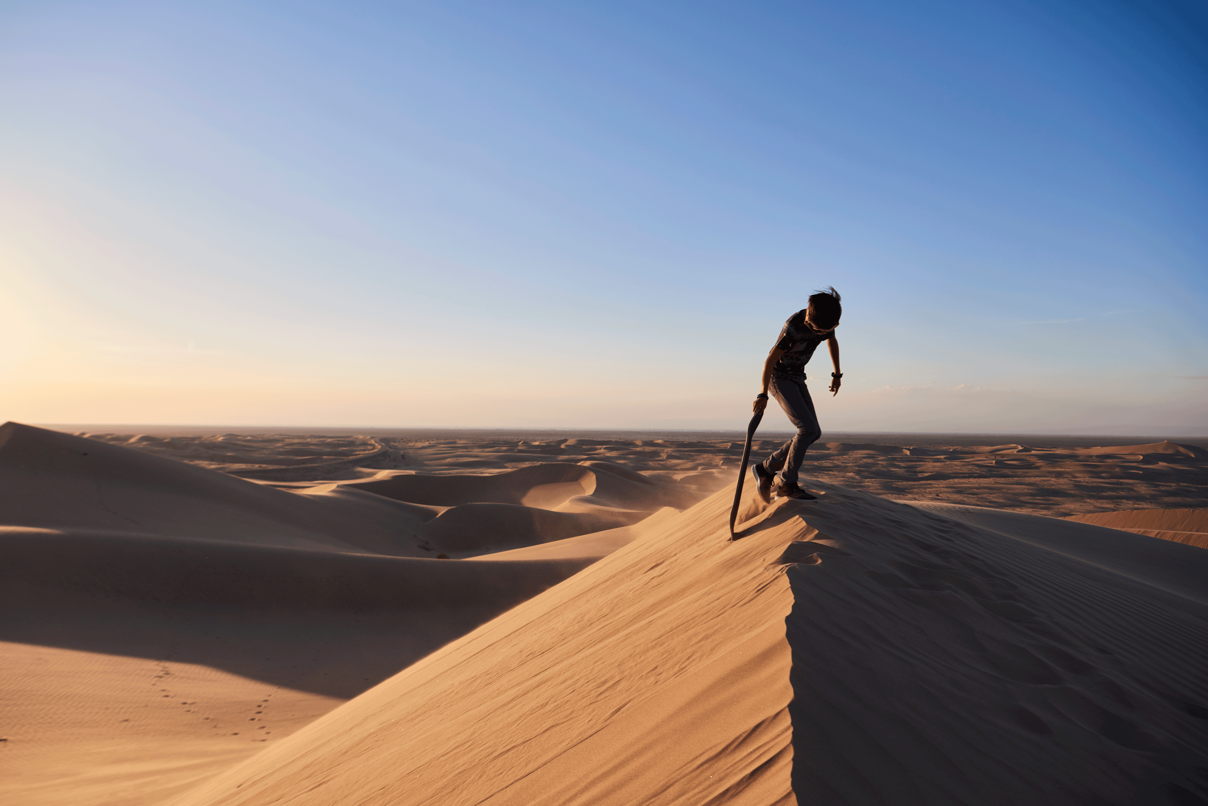 Boy sand surfing in the desert sand dunes in Glarnis California