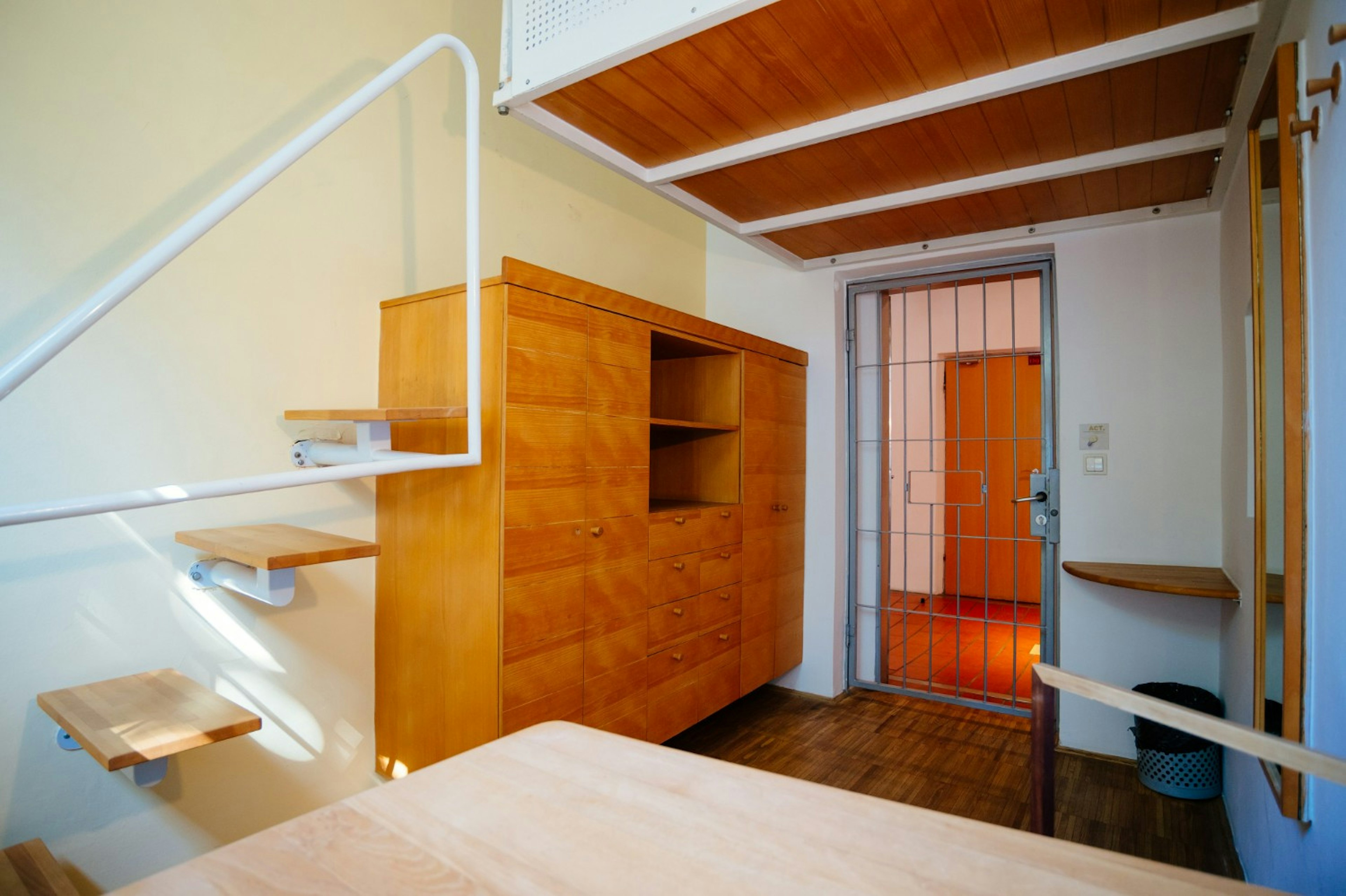 Inside a minimalist hostel room with a cell door.