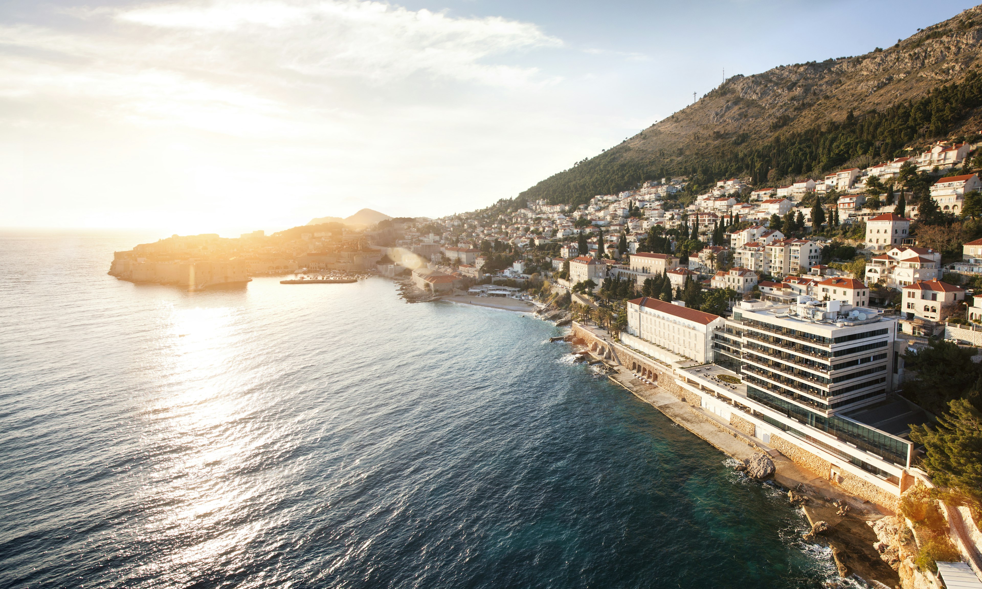 The exterior of the Hotel Excelsior on the edge of a bay with Old Town Dubrovnik in the background