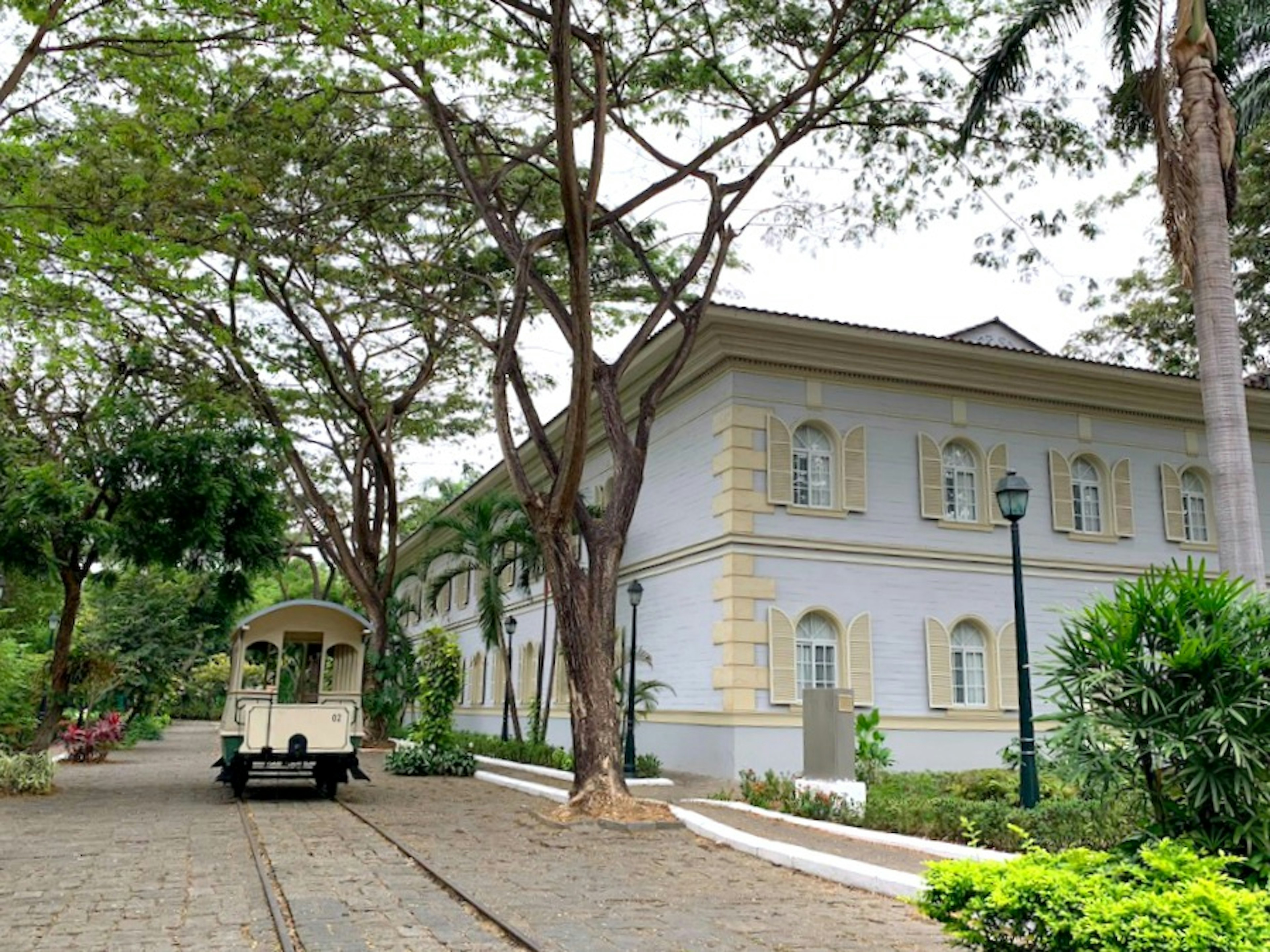 A trolly is parked on a cobbled stone street next to light-colored hotel