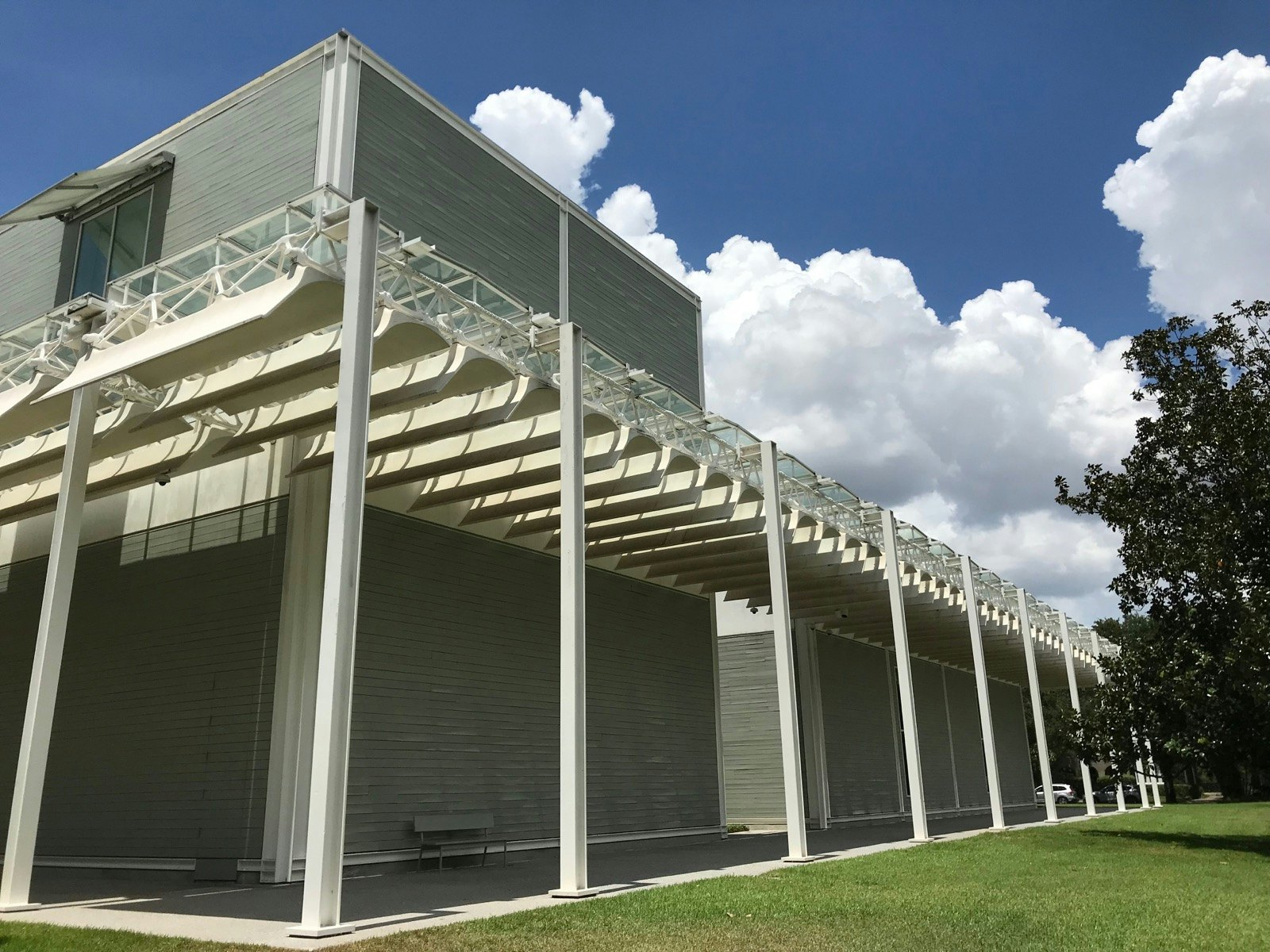 The exterior of a gray museum, with a white trellis, is shown in front of a brilliant blue sky. © Lisa Dunford / Ĵý