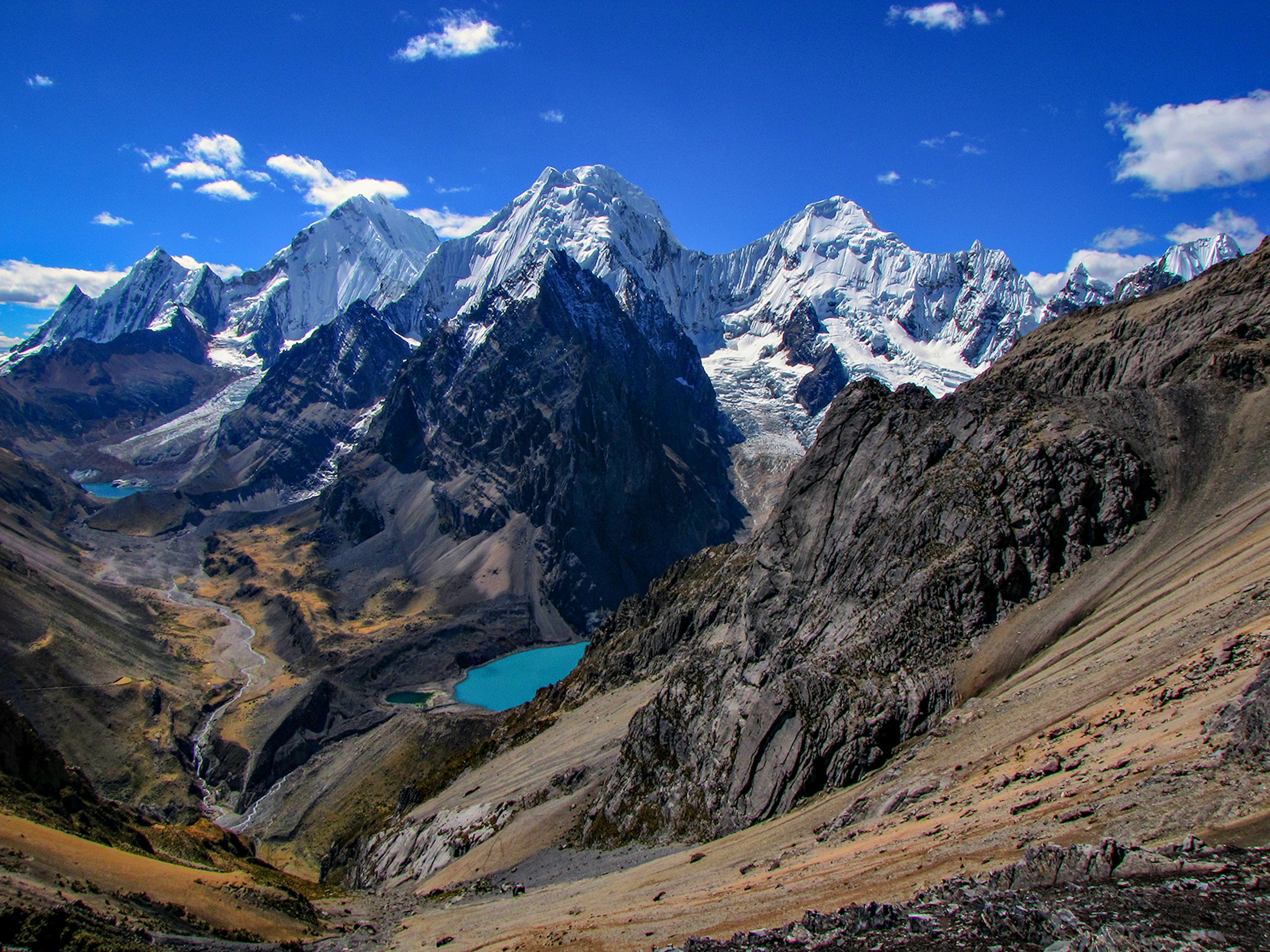 A panoramic shot of craggy snow-covered peaks with a blue glacial lagoon in the valley © Michael Mellinger / Getty Images