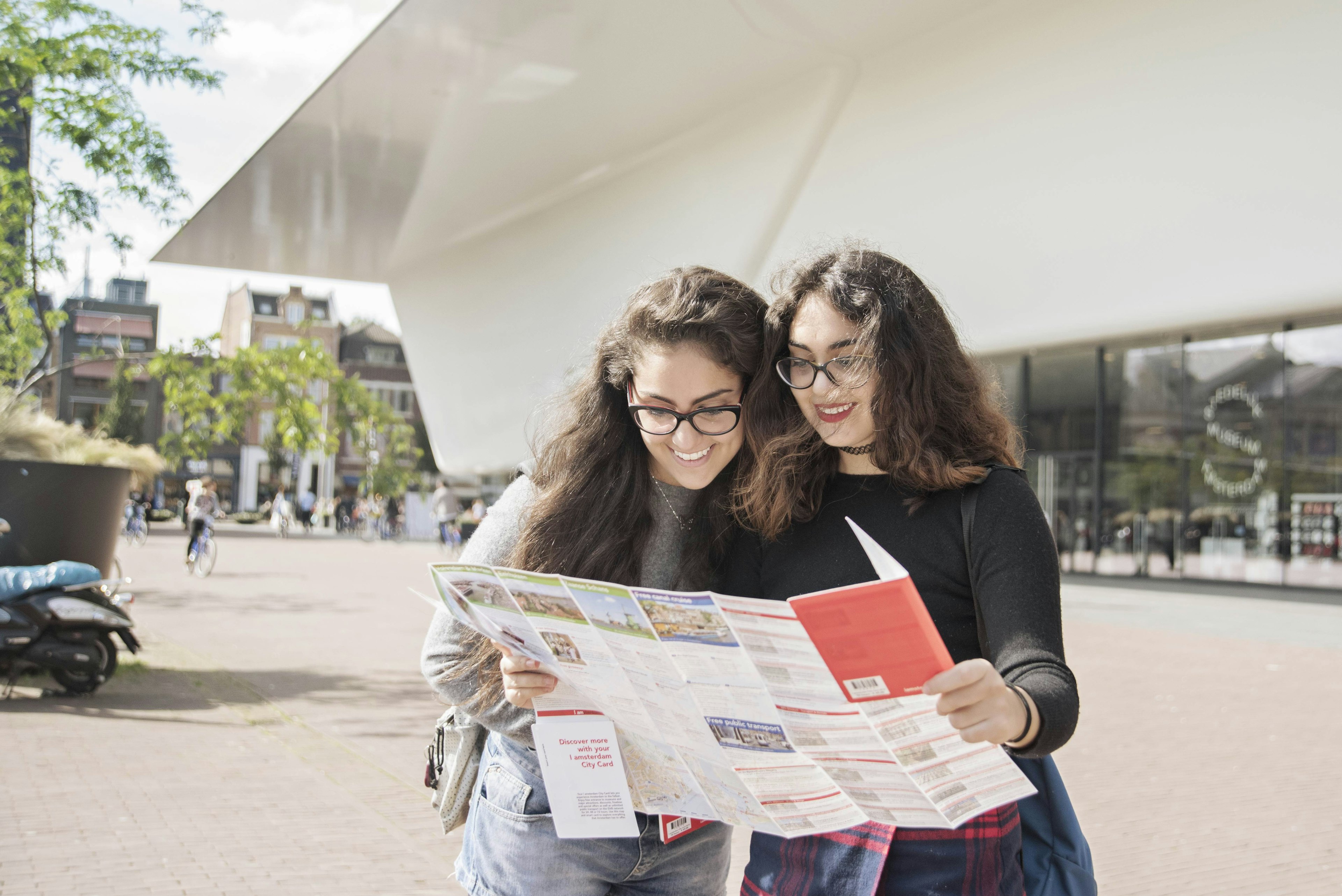 Two young women consult a map outside a museum