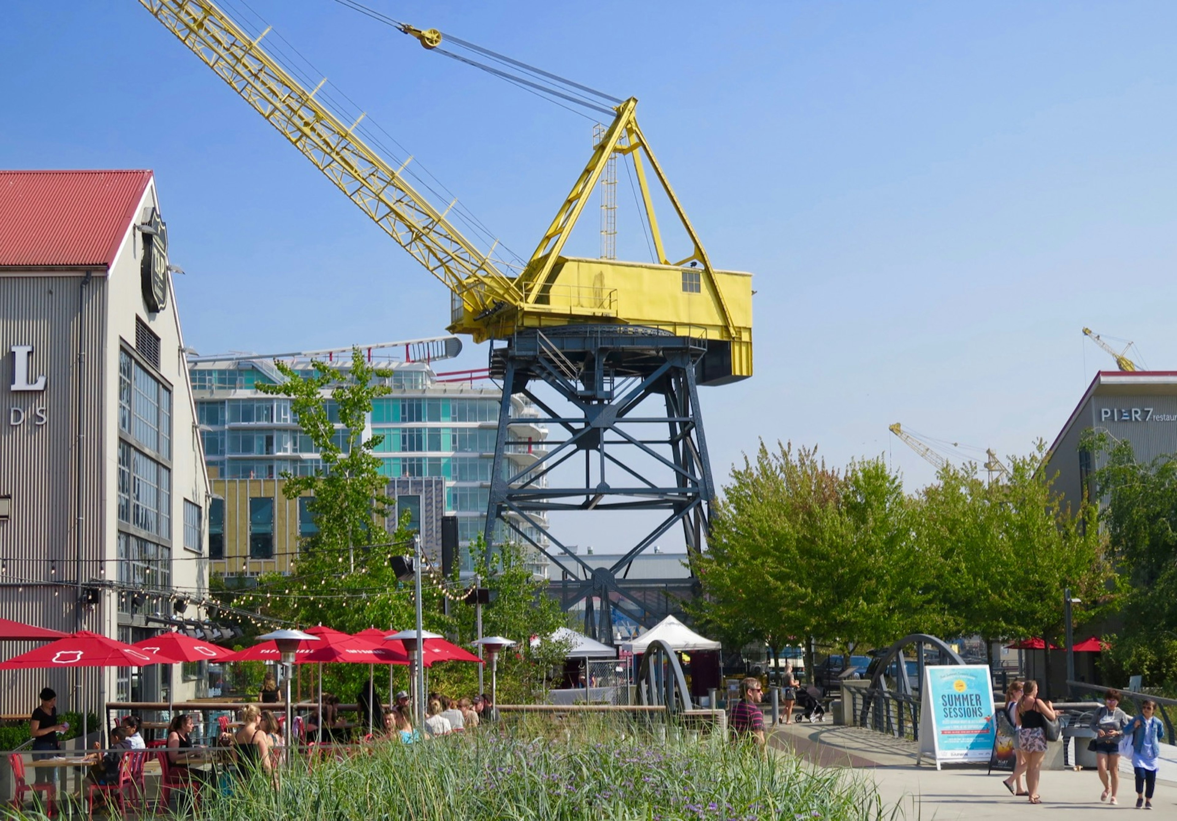 A massive yellow crane rises above a park with umbrellas and a building in the background © John Lee / ϰϲʿ¼