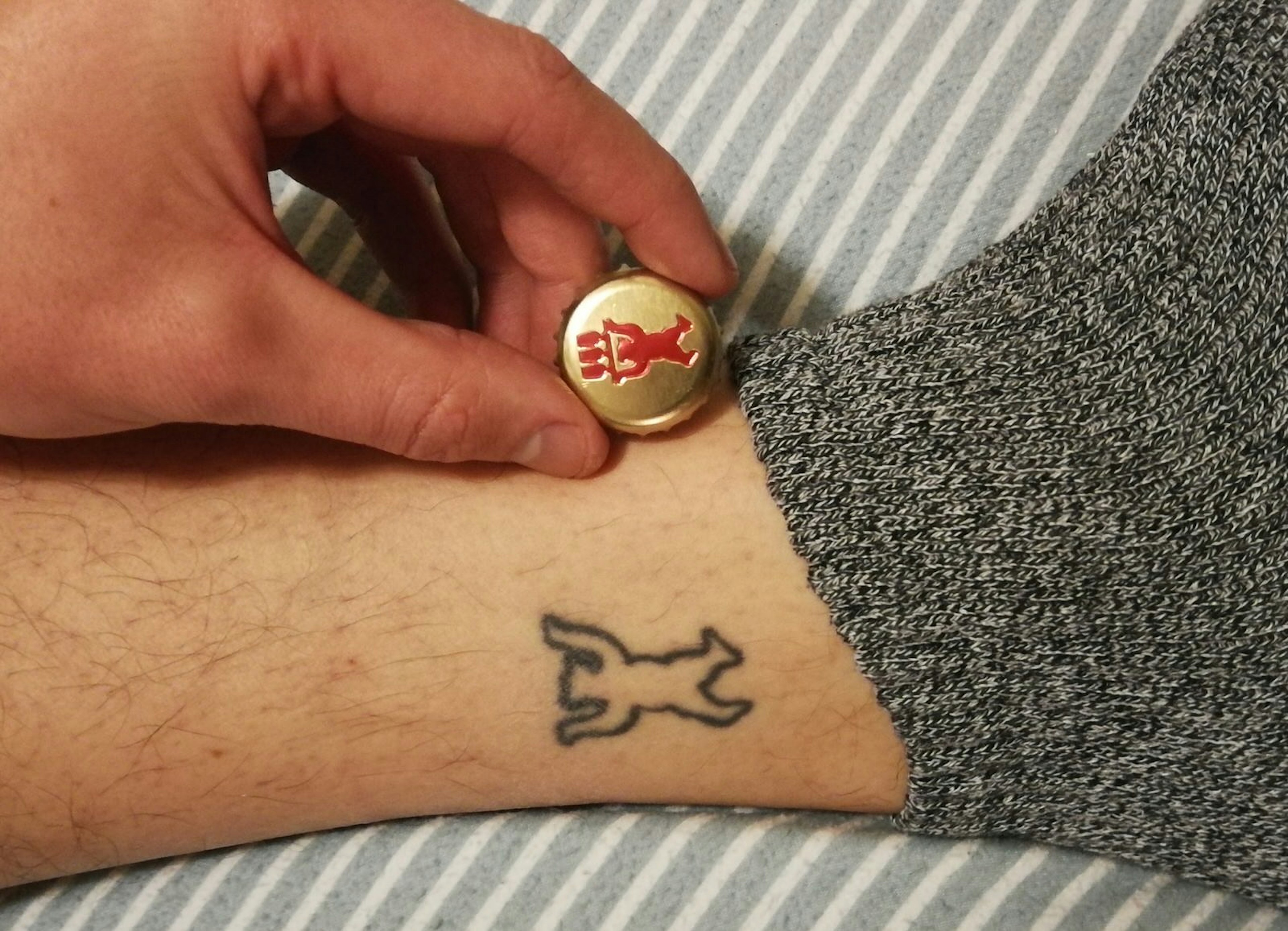 A small tattoo of a bear with the corresponding beer bottle cap it was copied from