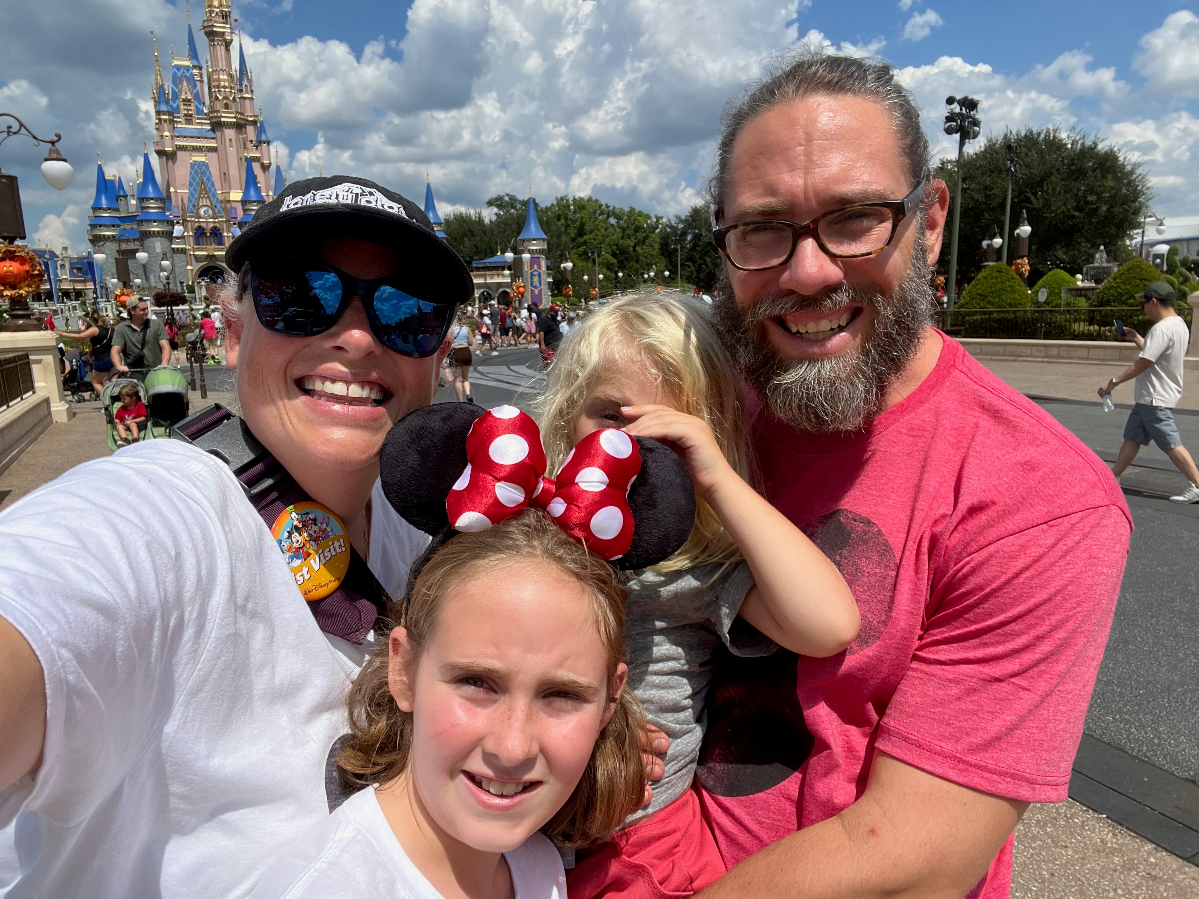 Two adults and two children pose for a photo in front of a castle at a theme park