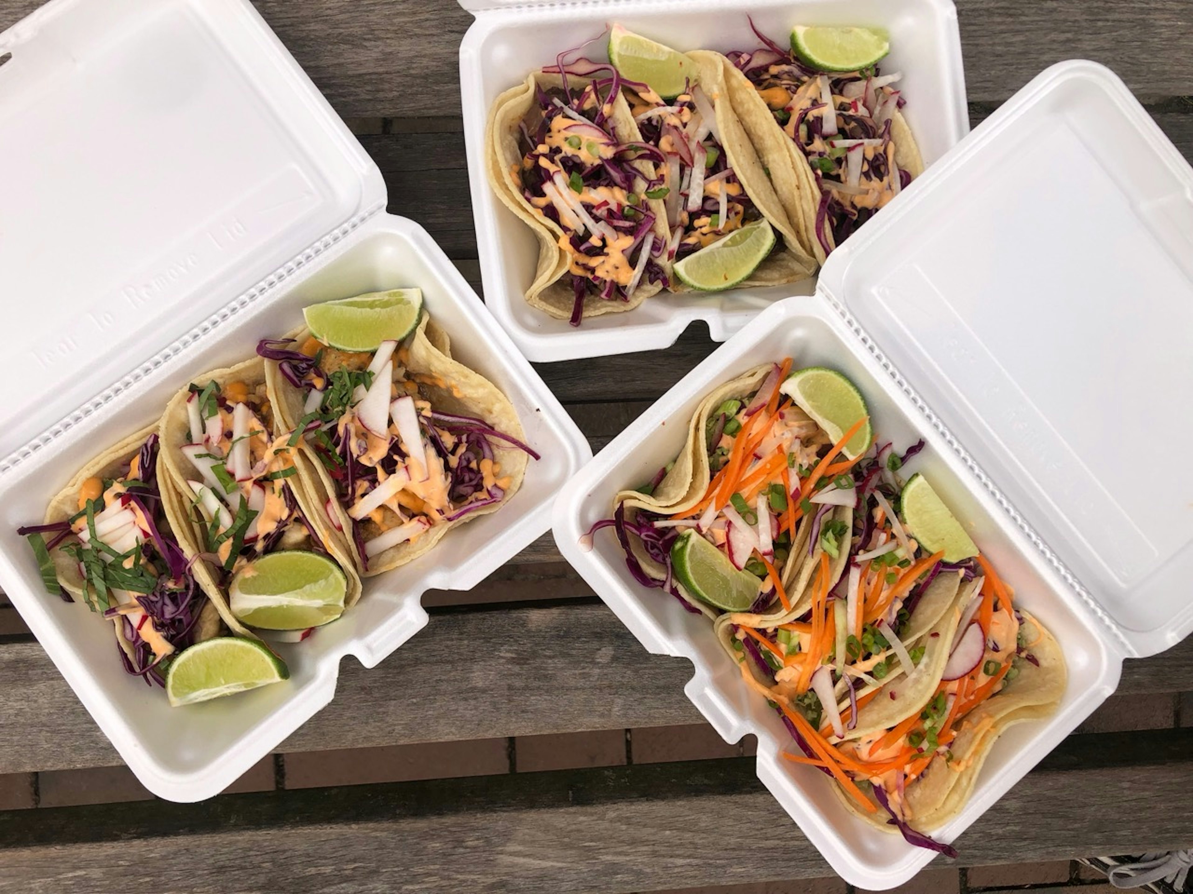 Three boxes of tacos from the Tyson Bees food truck, one edamame, one Thai basil chicken, and one Korean BBQ beef short rib.