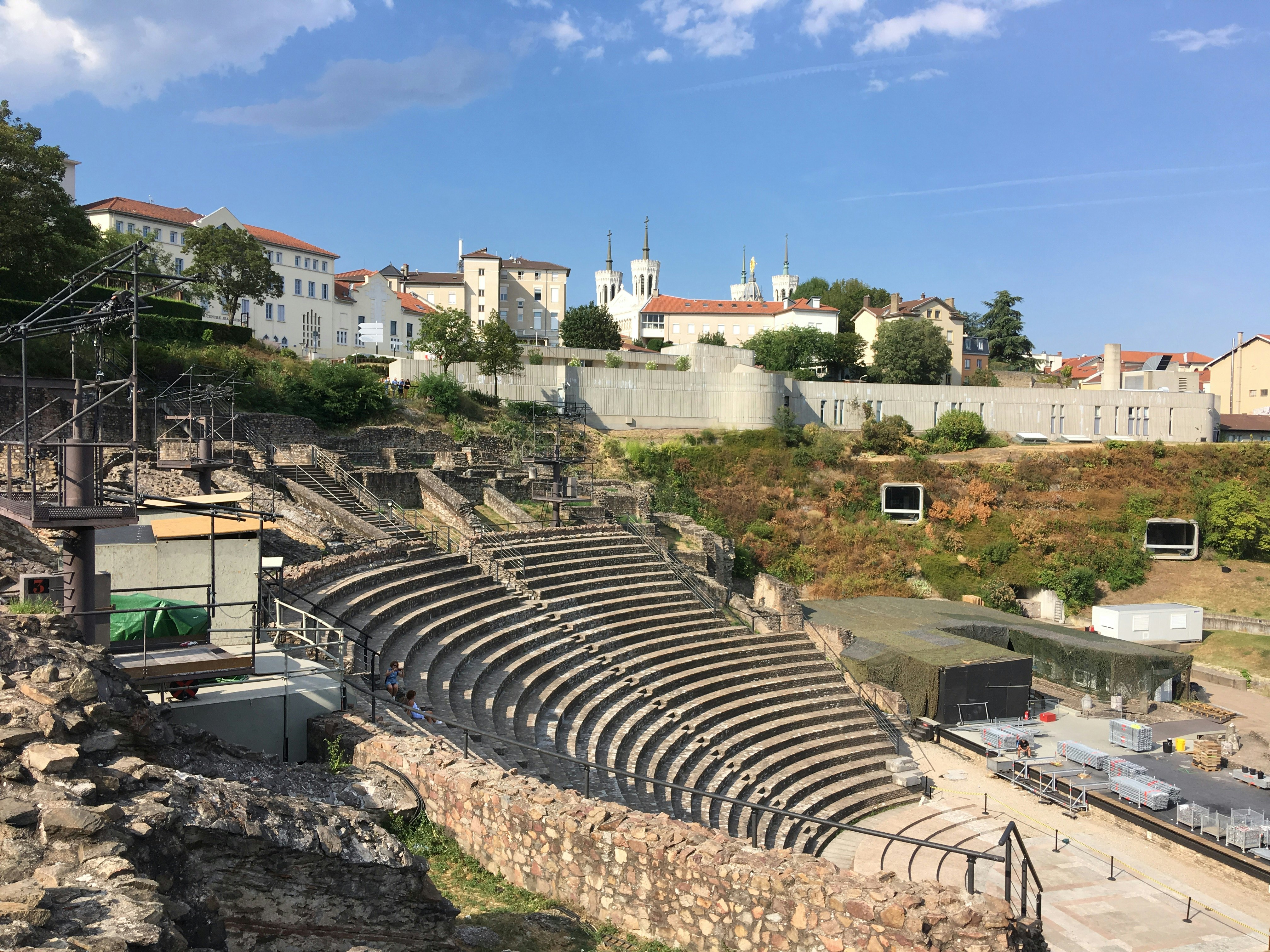 A Roman amphiteatre with some houses and the top of the basilica in the background