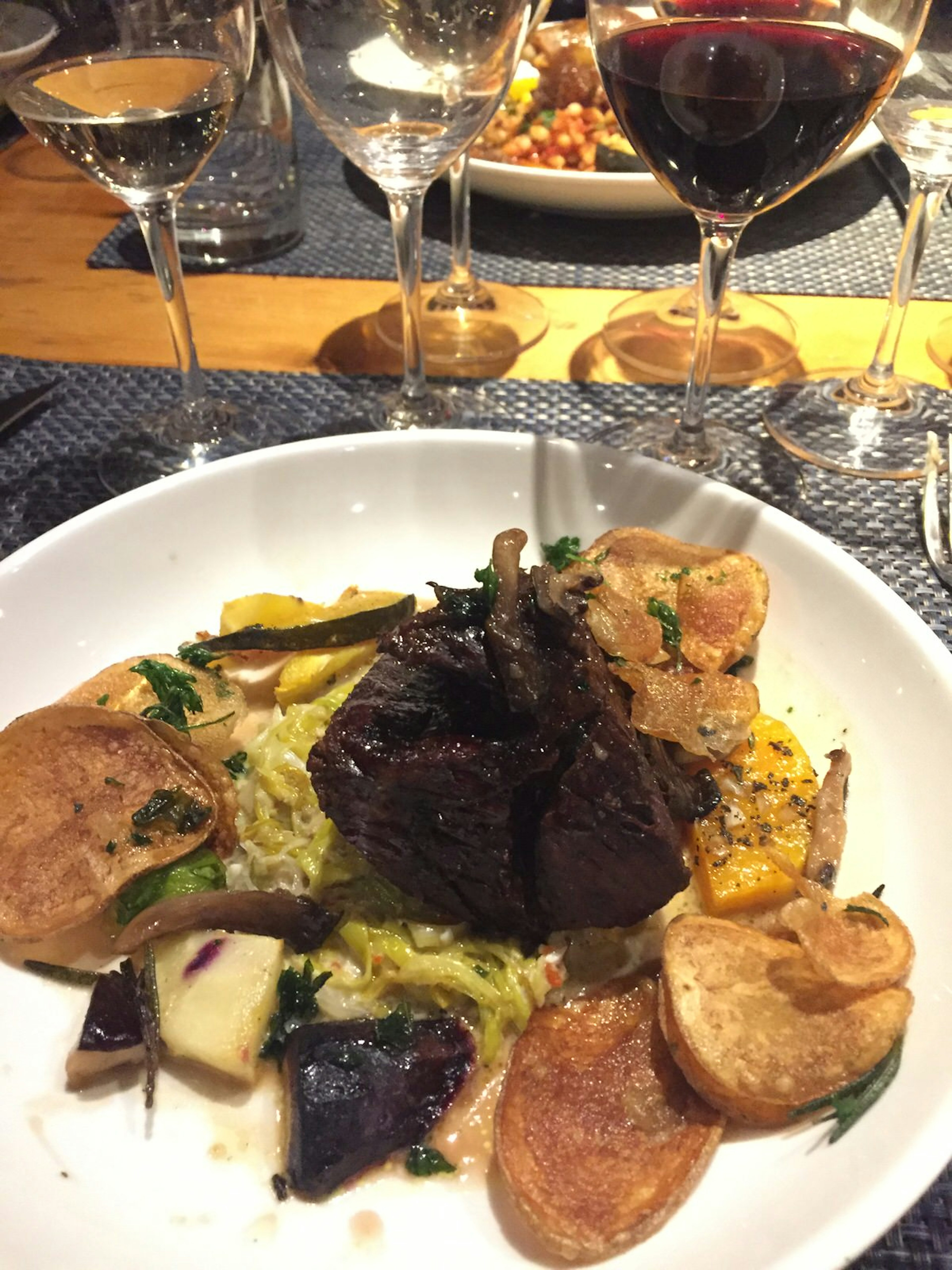 A plate of beef bits is shown with various wine glasses in the background.