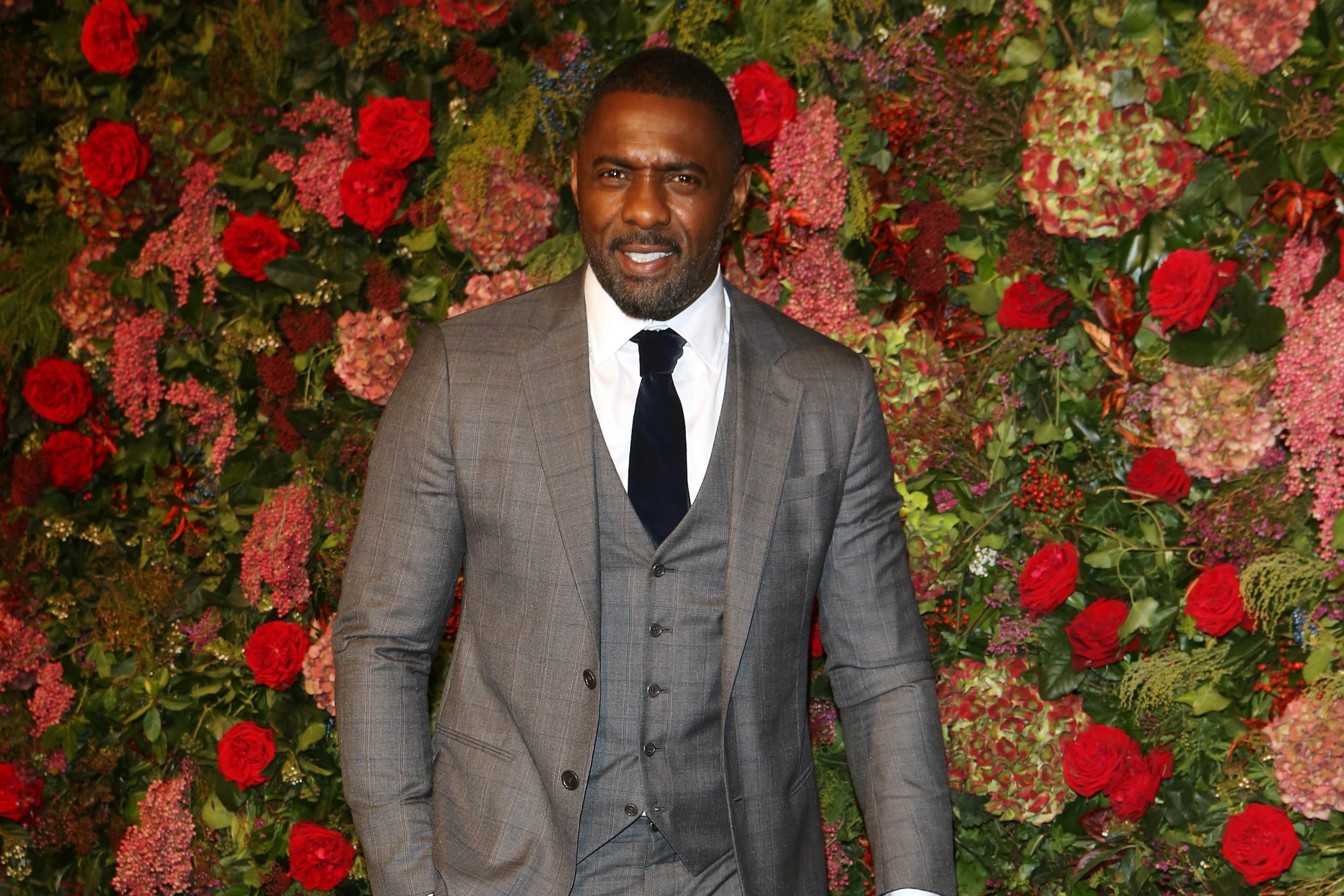 Actor Idris Elba in front of a flower wall