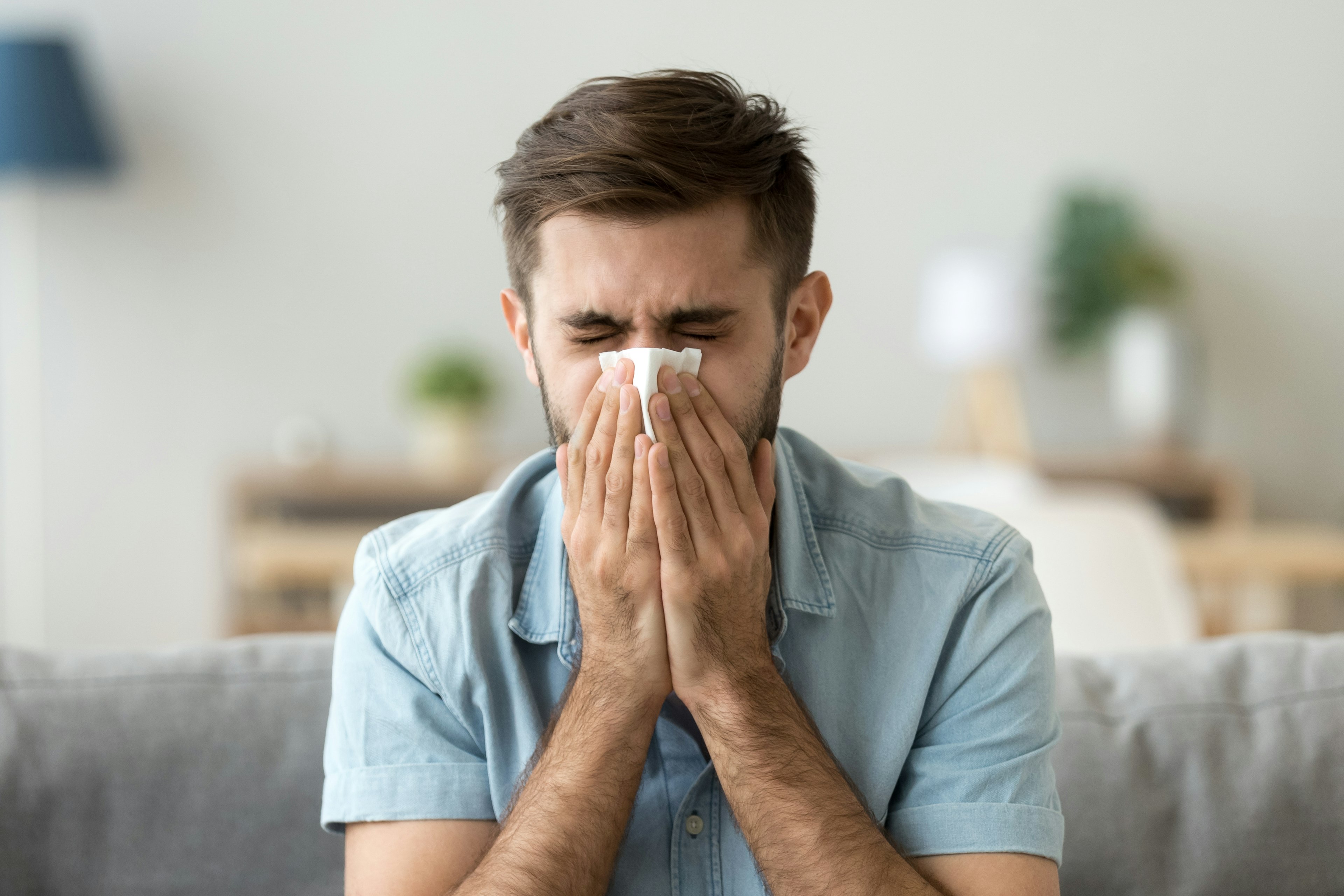 A man is sneezing into a tissue