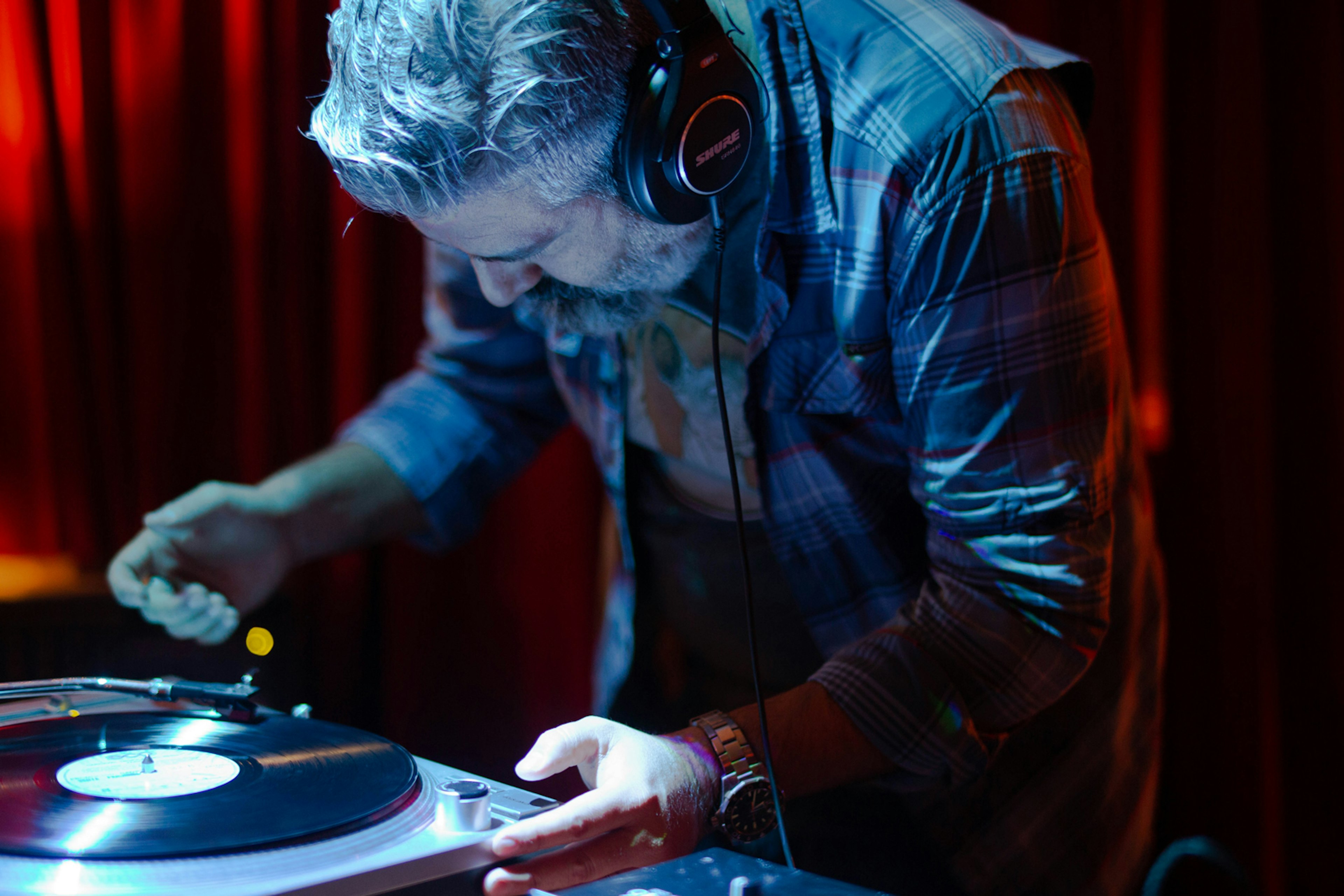 A close up of a man in headphones leaning over a turn table