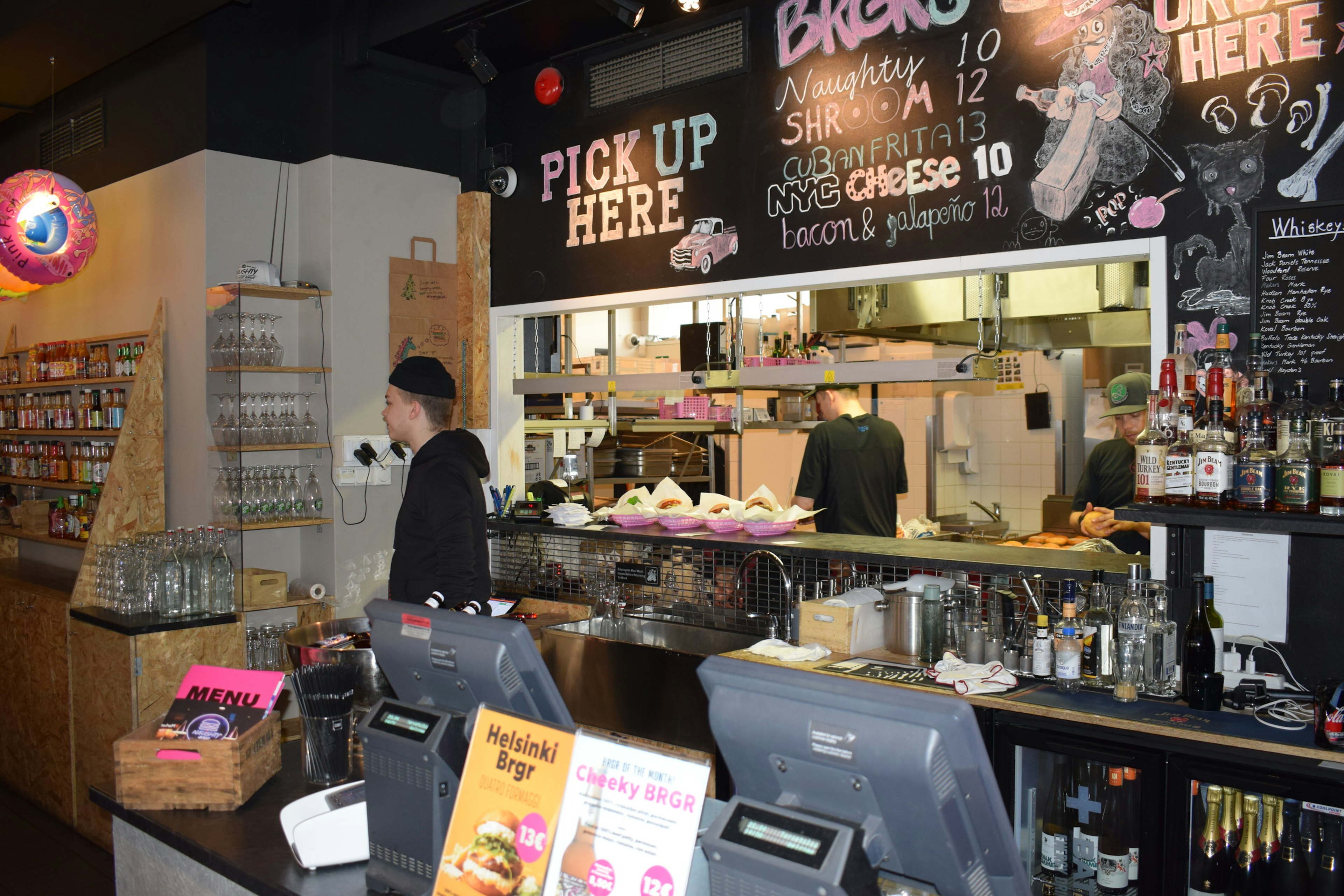 Interior view of Naughty Brgr, showing a member of staff behind the counter, in front of their chalk-wall menu © Violetta Teetor