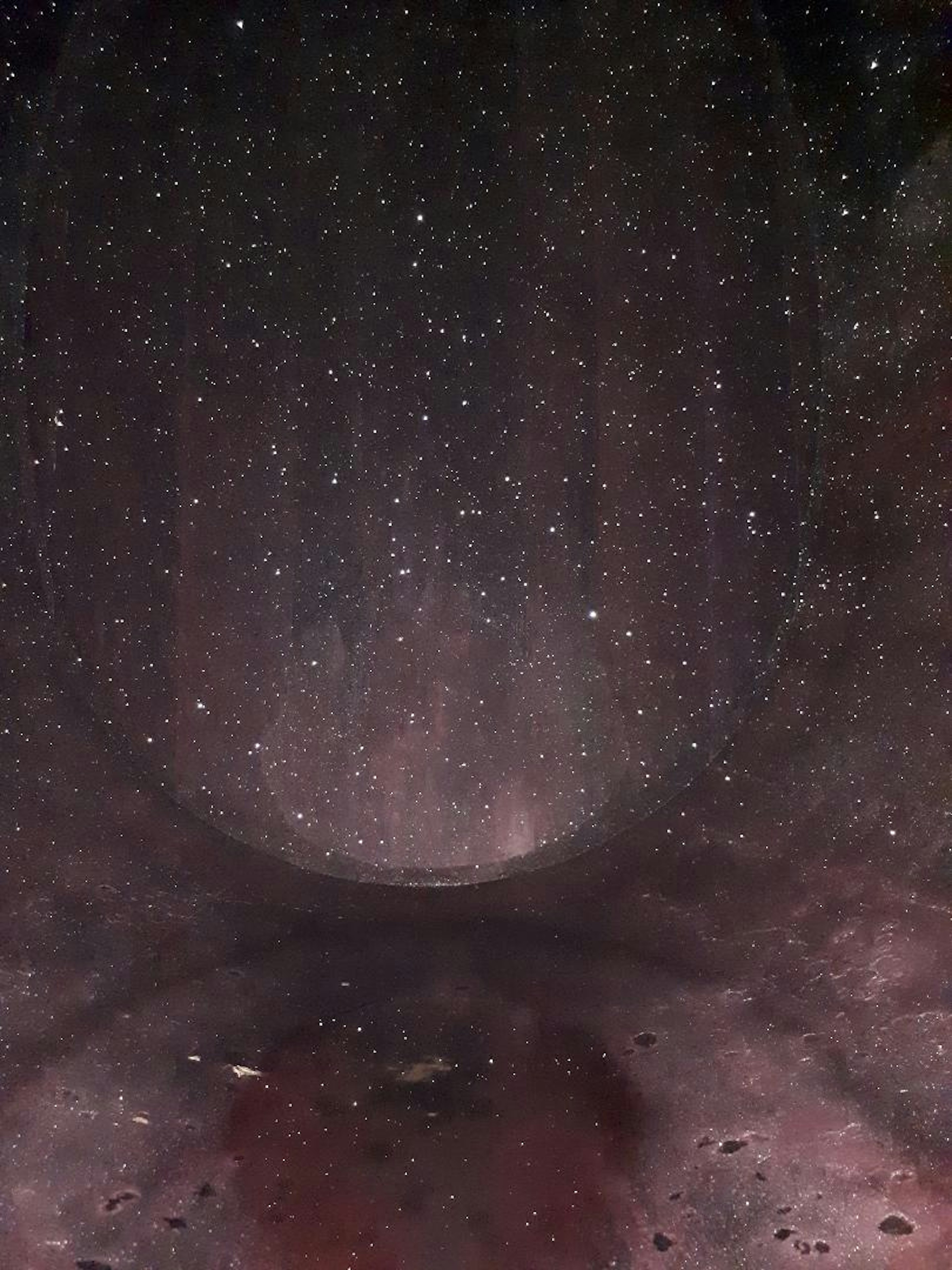 The inside of a wine barrel, as taken by German Wine Princess Inga Storck. The image is quite abstract, and looks almost like a shot of the Milky Way or a water color, with varying shades of deep reds, browns, purples, and blacks, splattered with white spots caused by crystals inside the barrel reflecting the flash back at the camera.