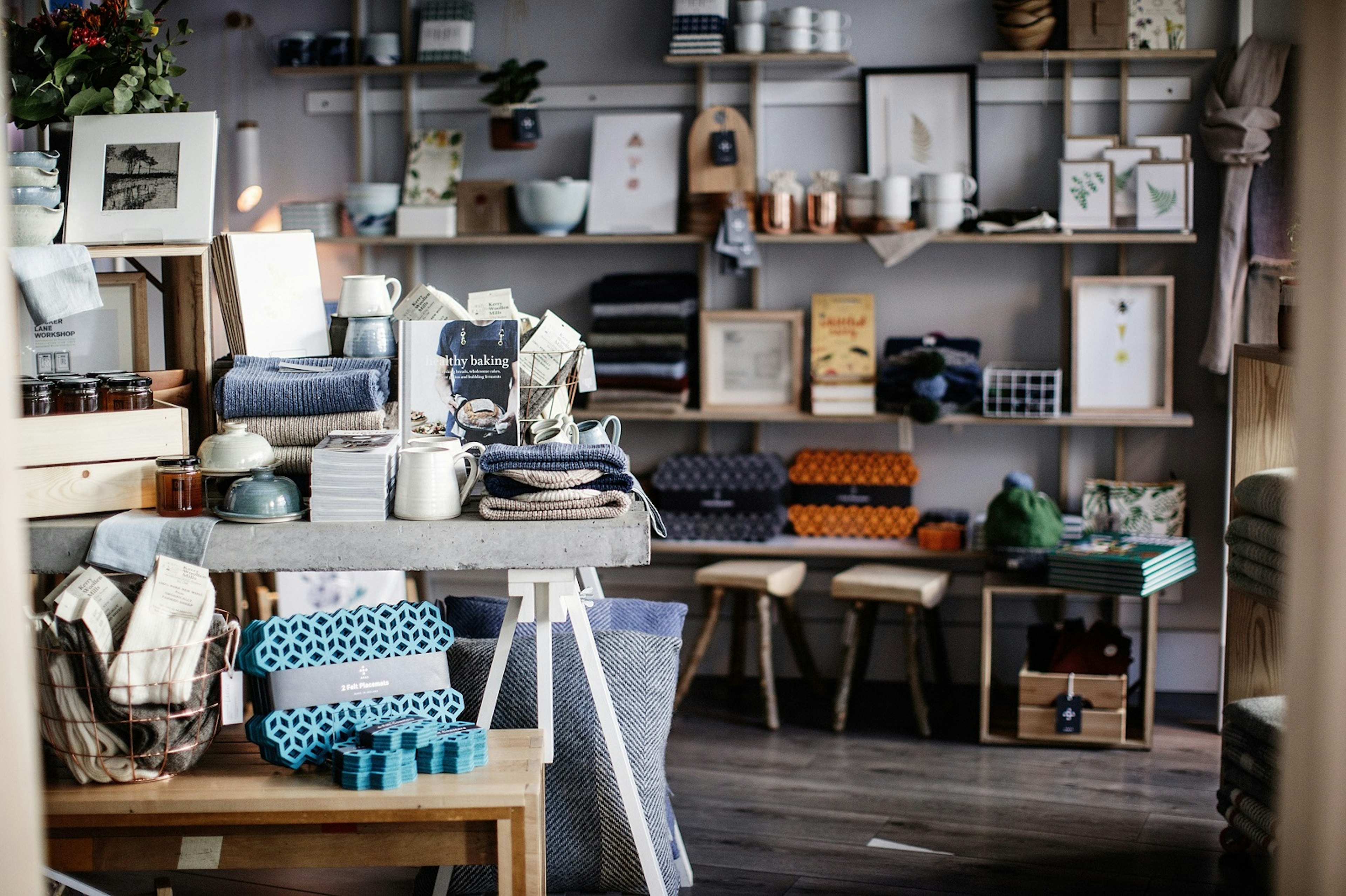 Dublin independent shops - the interior of the Irish Design Shop which is bursting with homewares, stools, woolly blankets and books piled on tables and shelves against the dark grey walls